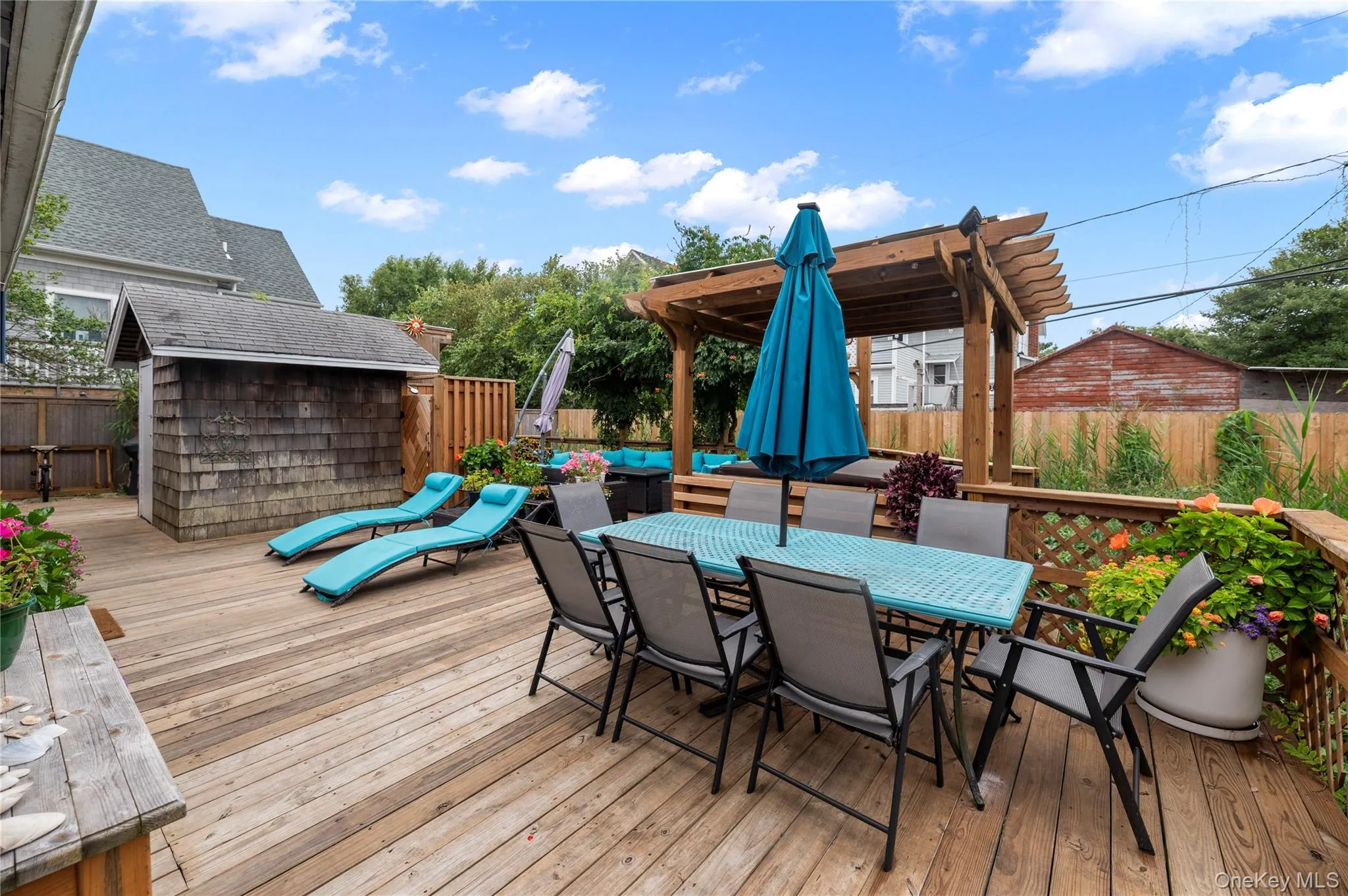 Wooden deck with outdoor dining area, a fenced backyard, and a storage unit Wooden deck with outdoor dining area, a fenced backyard, and a storage unit