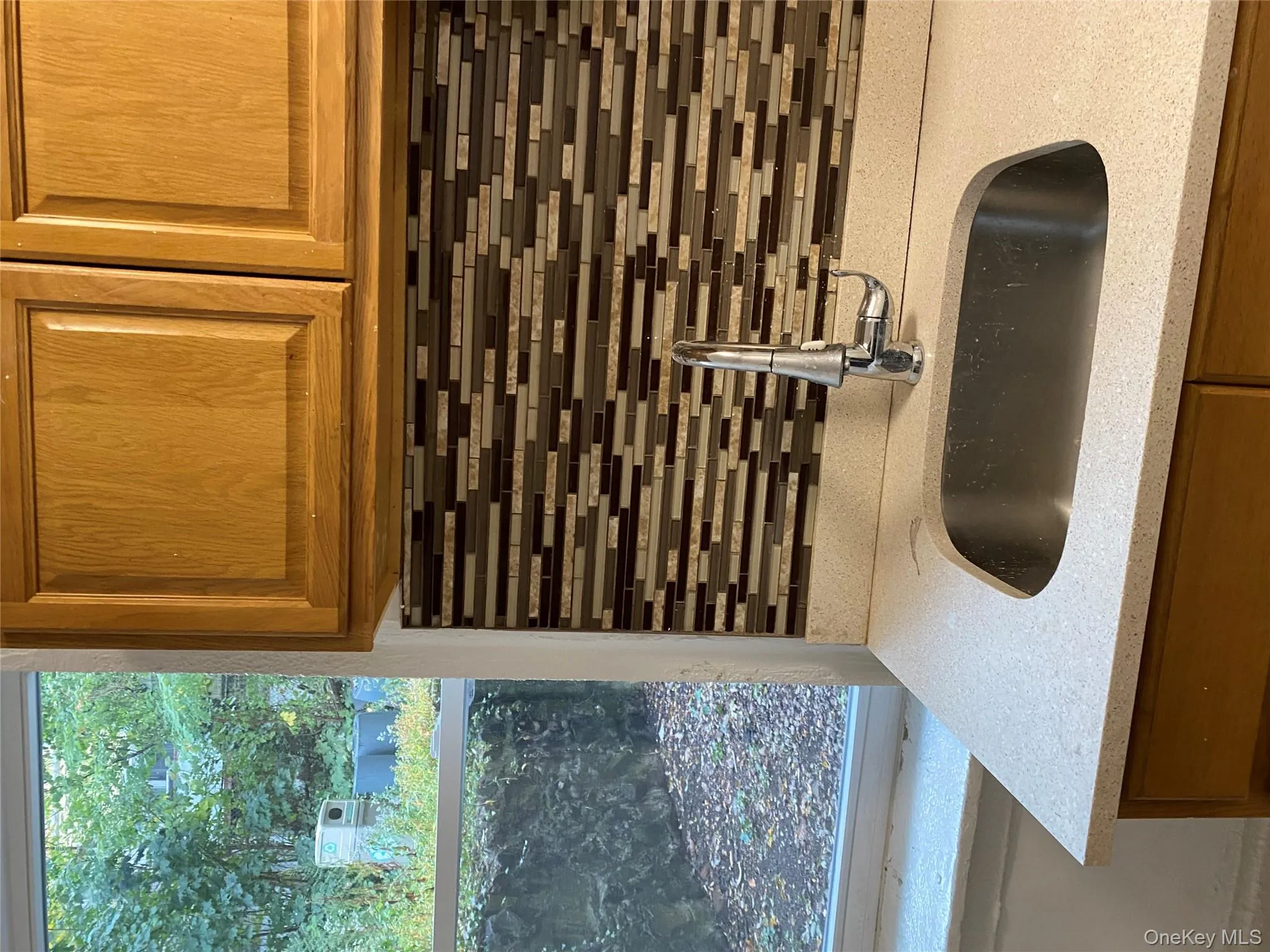 Kitchen view of brown cabinetry, tasteful backsplash, and light stone counters Kitchen view of brown cabinetry, tasteful backsplash, and light stone counters