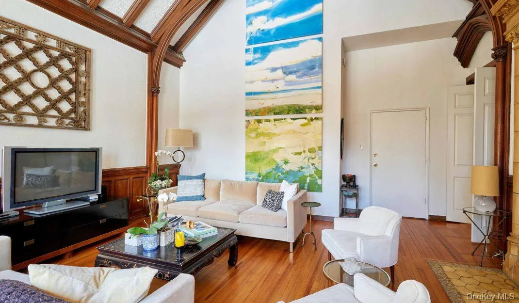 Living room featuring a high ceiling and wood finished floors Living room featuring a high ceiling and wood finished floors