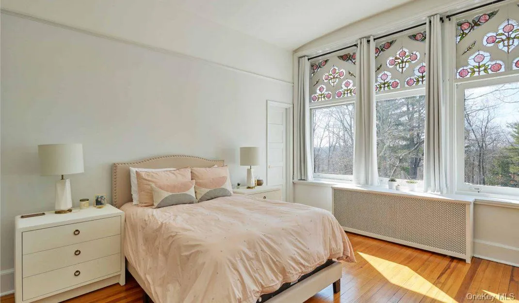 Bedroom with radiator heating unit and light wood-style flooring Bedroom with radiator heating unit and light wood-style flooring