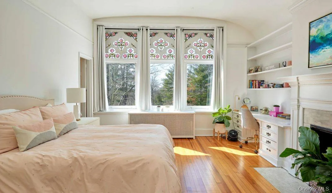 Bedroom featuring radiator heating unit, light wood finished floors, and a fireplace with flush hearth Bedroom featuring radiator heating unit, light wood finished floors, and a fireplace with flush hearth