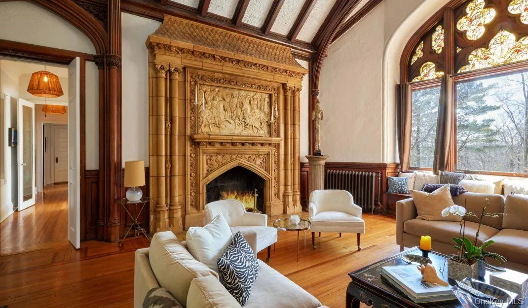 Living area with radiator heating unit, wainscoting, wood finished floors, a high end fireplace, and high vaulted ceiling Living area with radiator heating unit, wainscoting, wood finished floors, a high end fireplace, and high vaulted ceiling