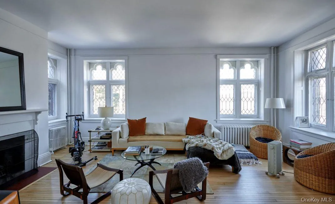 Living area featuring wood finished floors, radiator heating unit, and a fireplace with flush hearth Living area featuring wood finished floors, radiator heating unit, and a fireplace with flush hearth