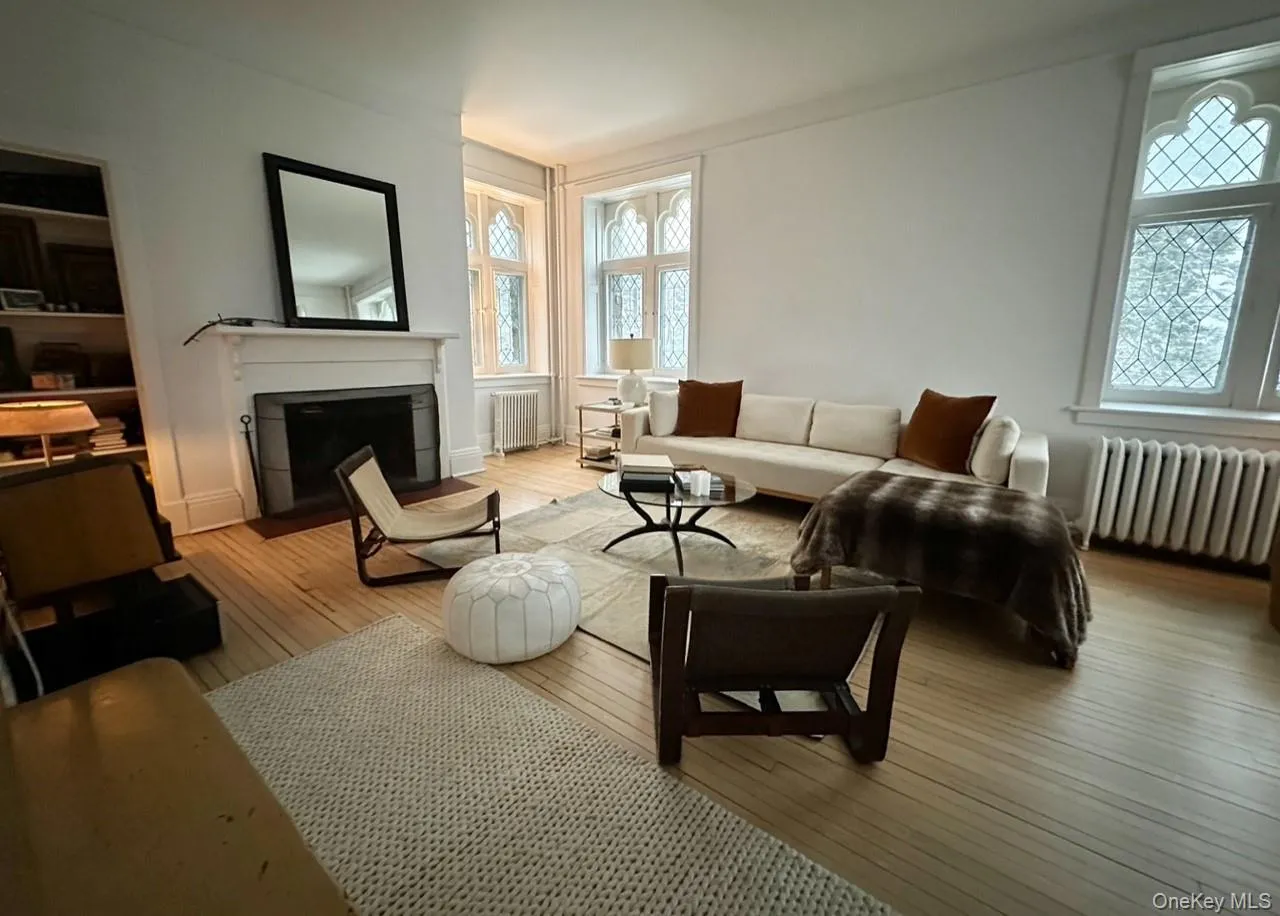 Living area featuring radiator heating unit, hardwood / wood-style floors, and a fireplace with flush hearth Living area featuring radiator heating unit, hardwood / wood-style floors, and a fireplace with flush hearth