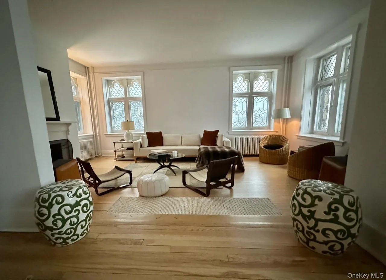 Living area featuring hardwood / wood-style flooring, healthy amount of natural light, a fireplace, and radiator heating unit Living area featuring hardwood / wood-style flooring, healthy amount of natural light, a fireplace, and radiator heating unit