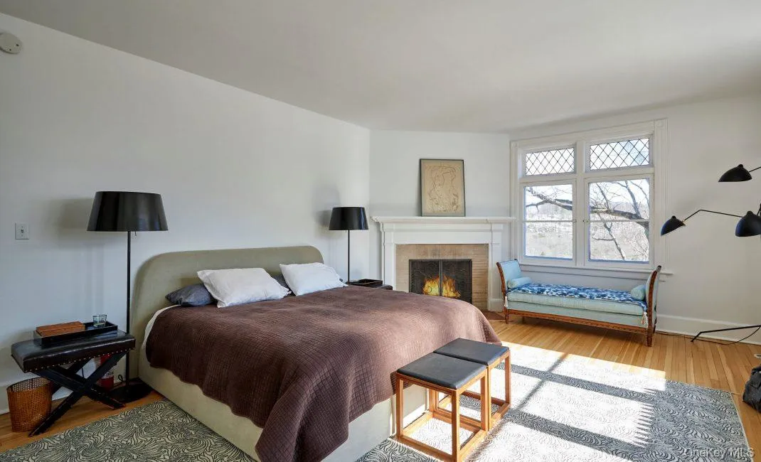 Bedroom featuring wood finished floors and a lit fireplace Bedroom featuring wood finished floors and a lit fireplace