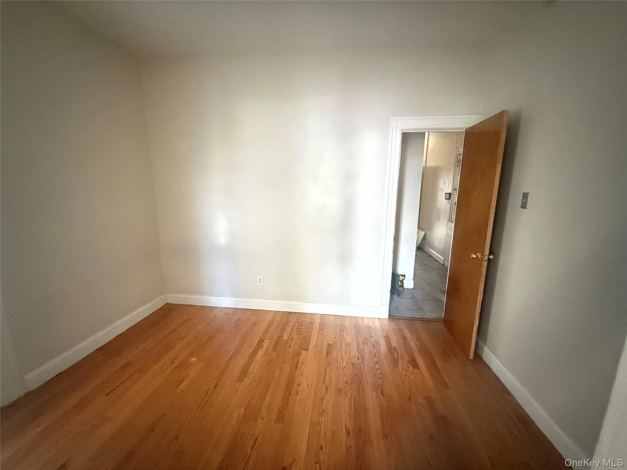 Unfurnished room with baseboards and wood finished floors Unfurnished room with baseboards and wood finished floors