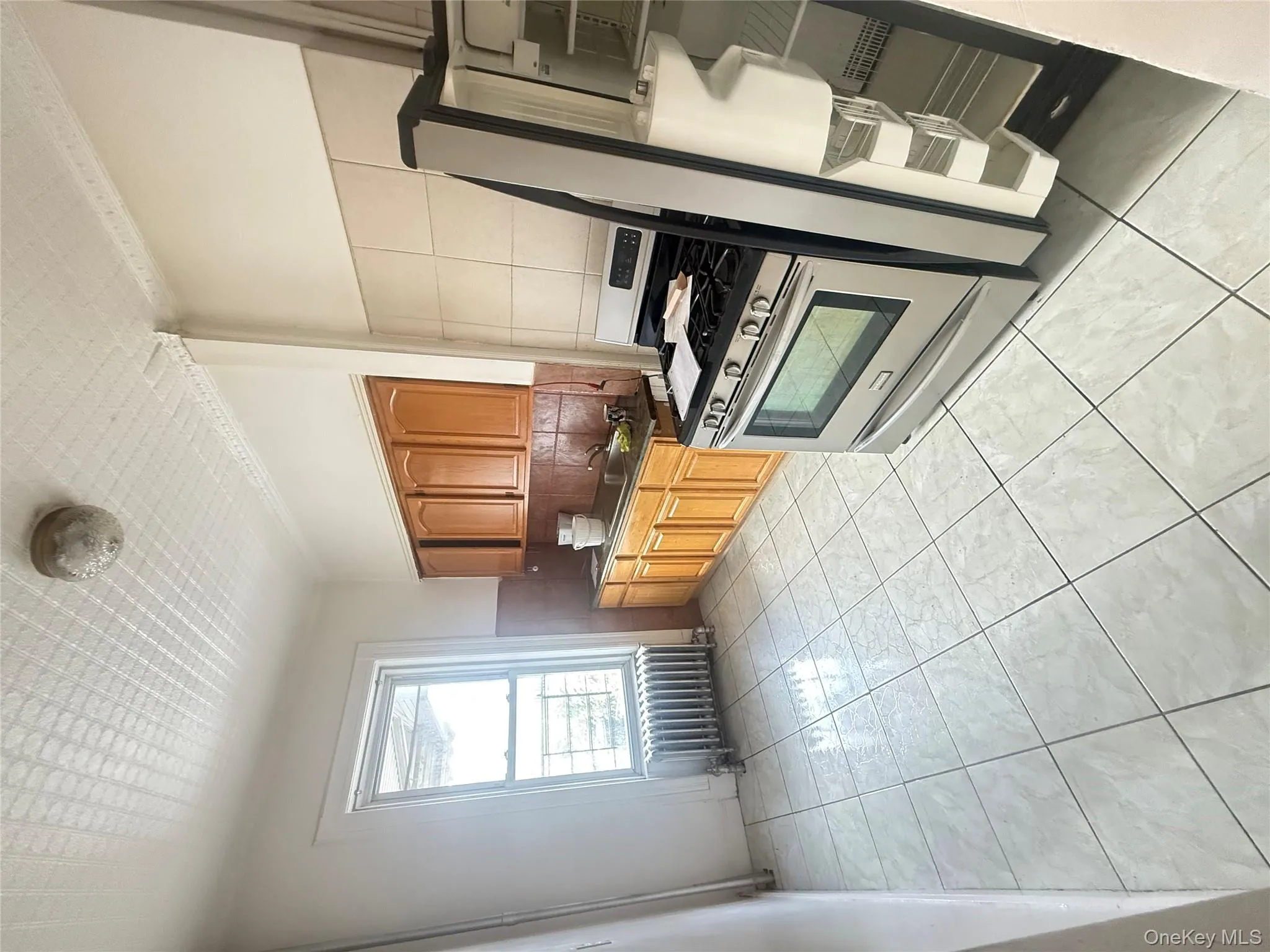 Kitchen featuring brown cabinetry, range, radiator, tasteful backsplash, and dark countertops Kitchen featuring brown cabinetry, range, radiator, tasteful backsplash, and dark countertops