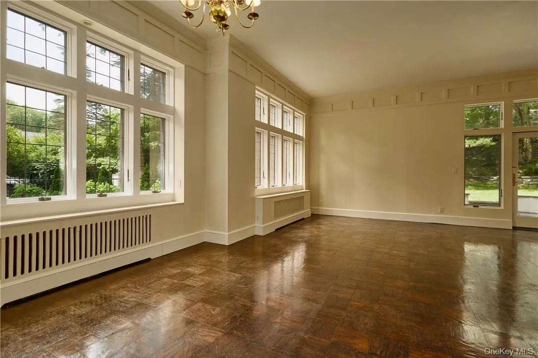 Unfurnished sunroom featuring radiator and an inviting chandelier Unfurnished sunroom featuring radiator and an inviting chandelier