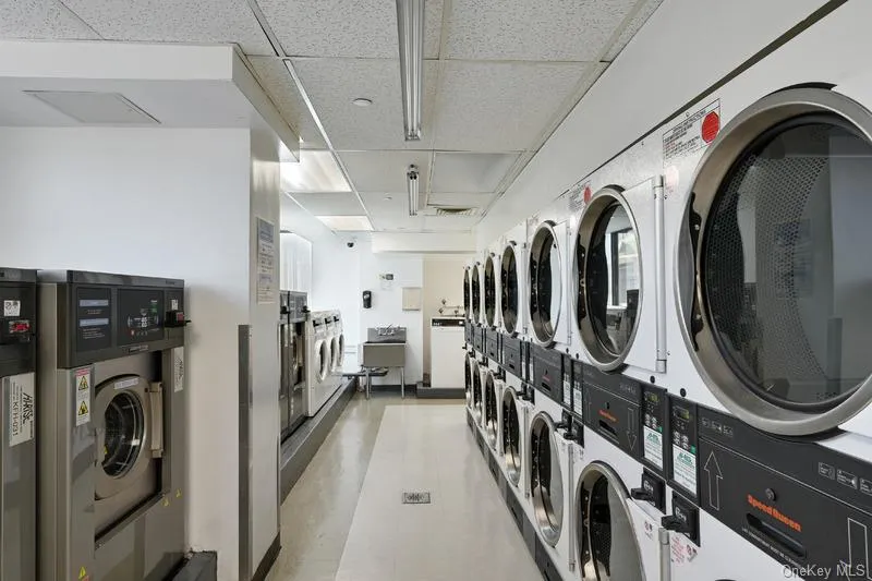 Communal laundry room featuring stacked washer / dryer and a drop ceiling Communal laundry room featuring stacked washer / dryer and a drop ceiling