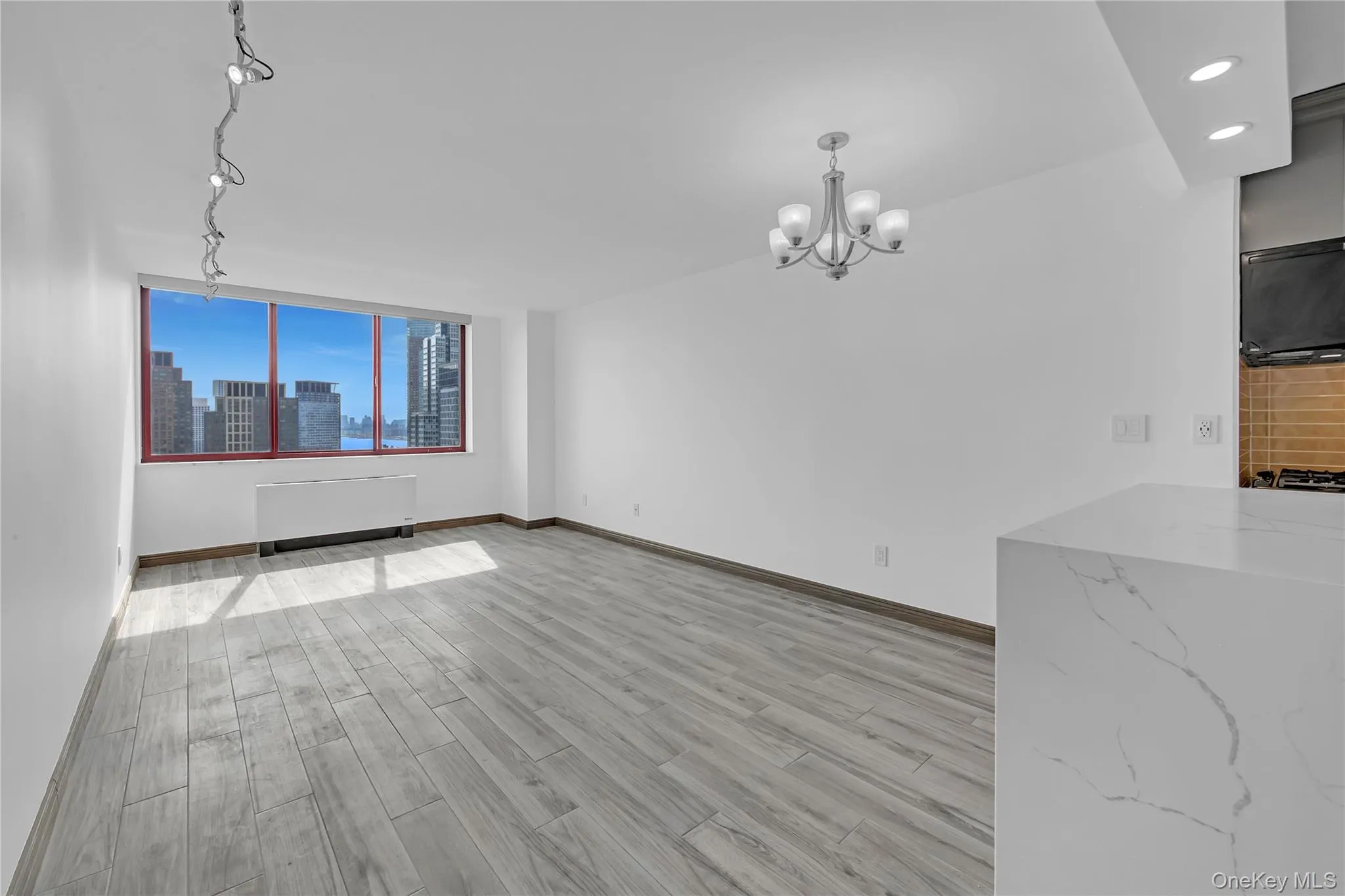 Unfurnished dining area with light wood-style flooring, a chandelier, a skyline view, radiator heating unit, and recessed lighting Unfurnished dining area with light wood-style flooring, a chandelier, a skyline view, radiator heating unit, and recessed lighting