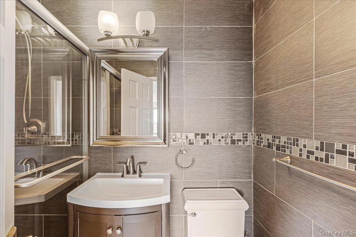 Bathroom featuring tile walls, vanity, and backsplash Bathroom featuring tile walls, vanity, and backsplash