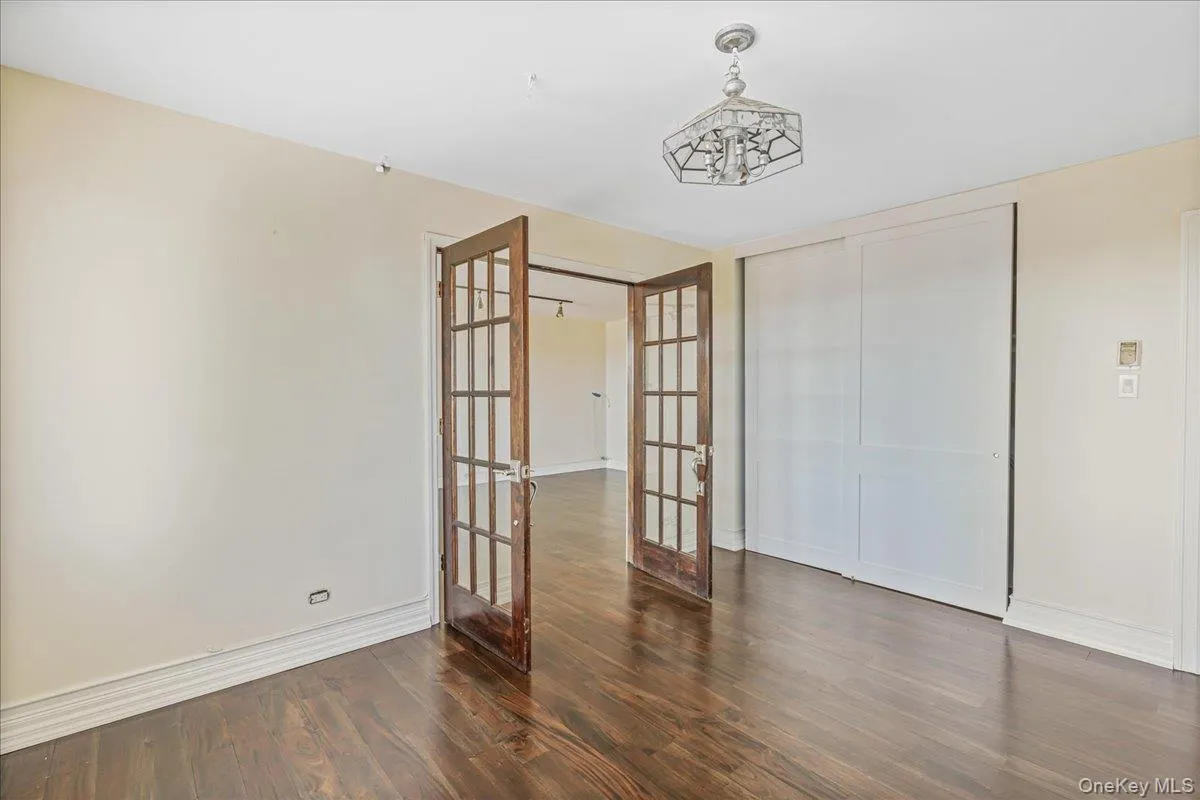 Unfurnished bedroom with french doors, dark wood-style floors, and a closet Unfurnished bedroom with french doors, dark wood-style floors, and a closet