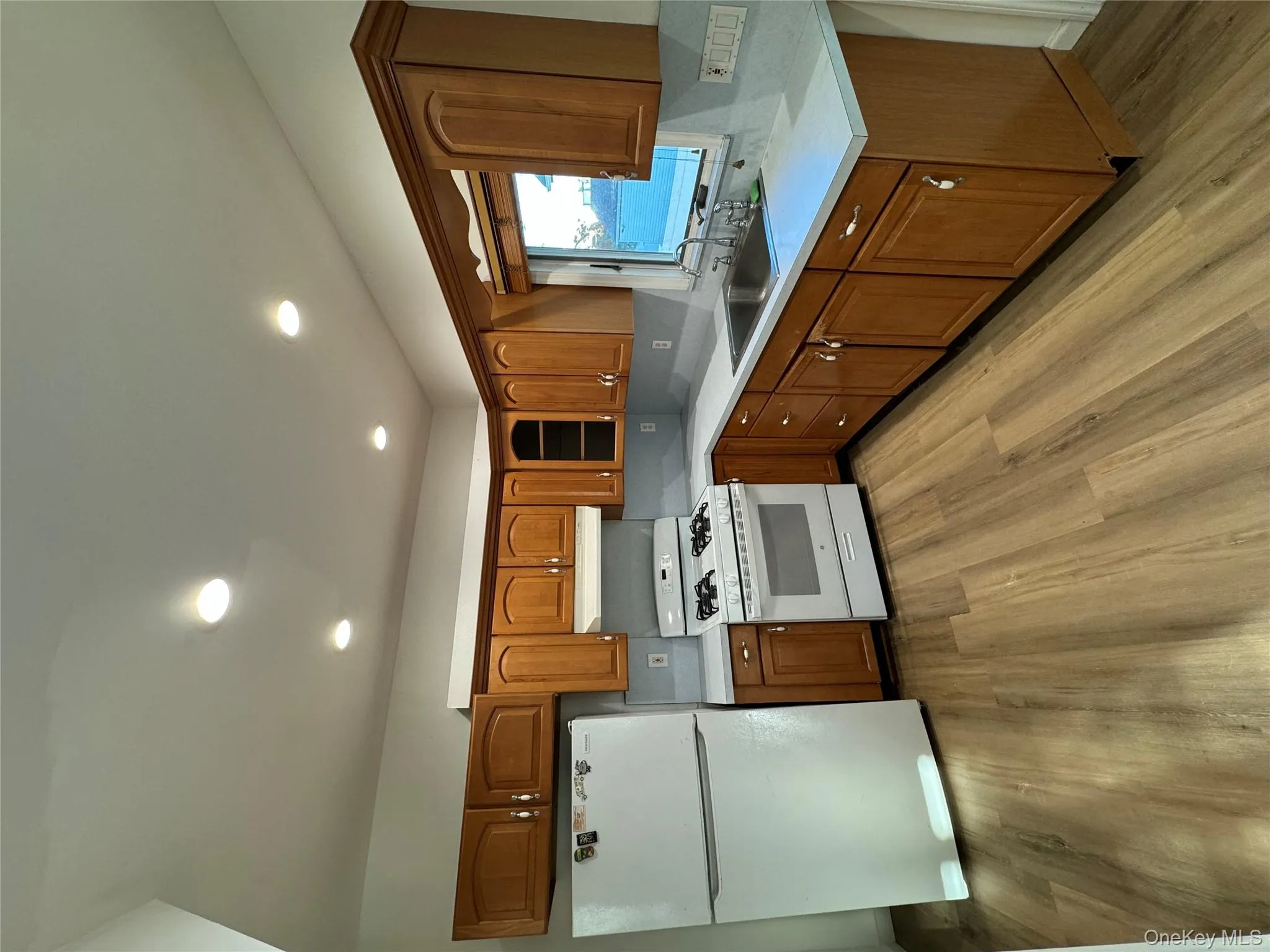 Kitchen with brown cabinets, fridge, recessed lighting, range, and light wood-style flooring Kitchen with brown cabinets, fridge, recessed lighting, range, and light wood-style flooring