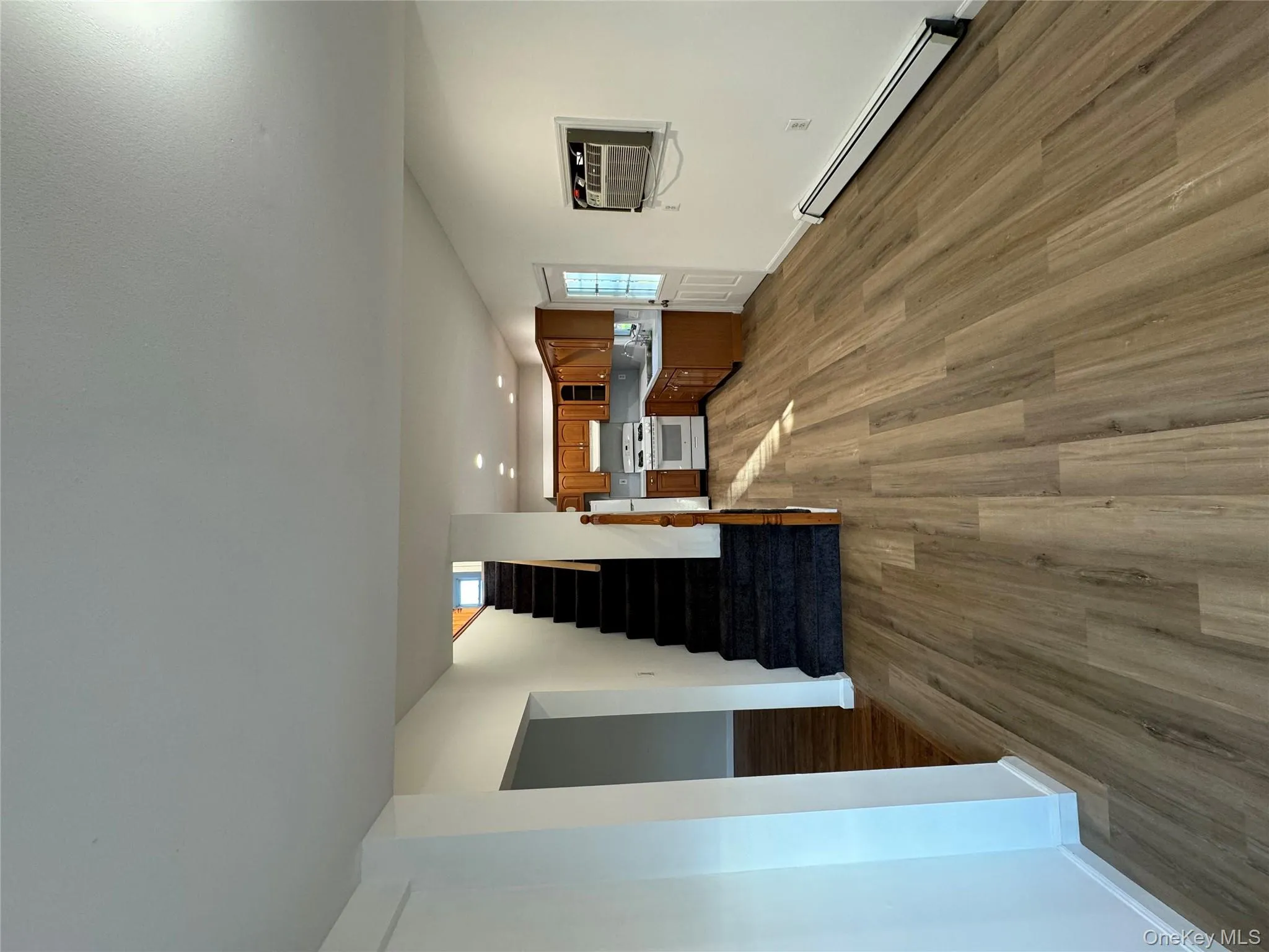 Unfurnished living room with a baseboard radiator, dark wood-style floors, stairs, a wall mounted AC, and recessed lighting Unfurnished living room with a baseboard radiator, dark wood-style floors, stairs, a wall mounted AC, and recessed lighting