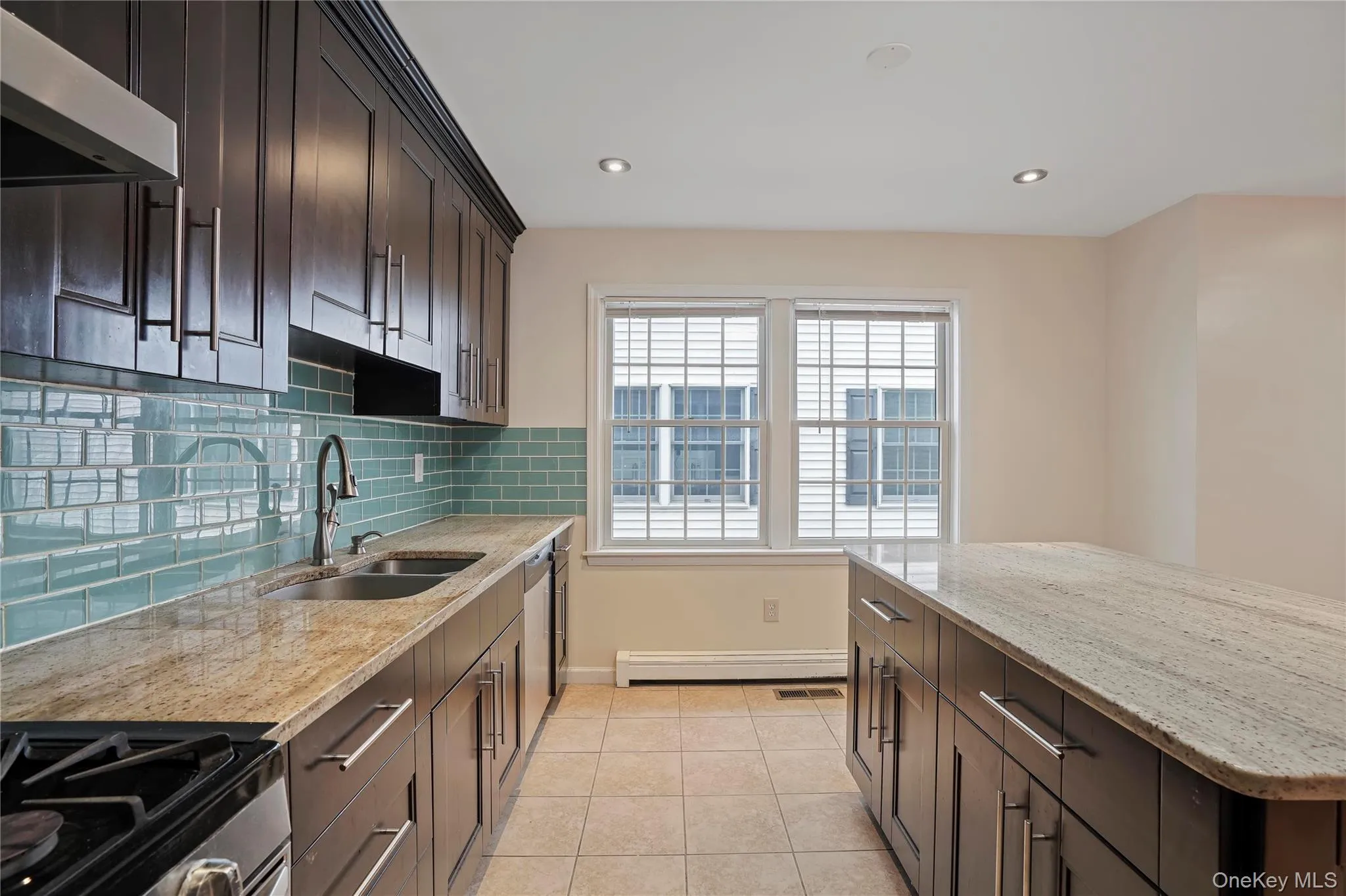 Kitchen with ventilation hood, light stone countertops, dark brown cabinets, appliances with stainless steel finishes, and recessed lighting Kitchen with ventilation hood, light stone countertops, dark brown cabinets, appliances with stainless steel finishes, and recessed lighting