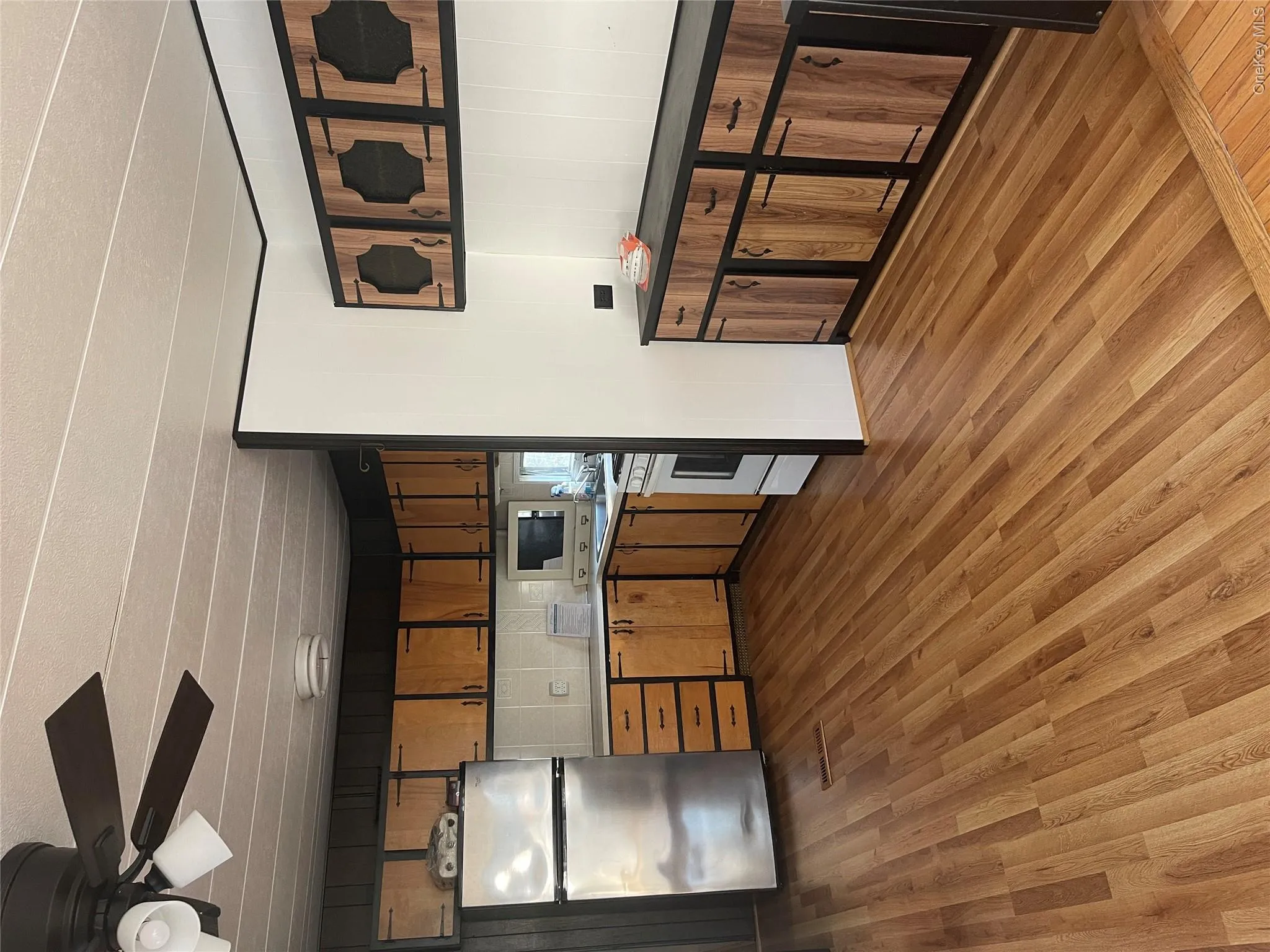 Kitchen with light wood-type flooring, fridge, light countertops, stainless steel gas stove, and brown cabinets Kitchen with light wood-type flooring, fridge, light countertops, stainless steel gas stove, and brown cabinets