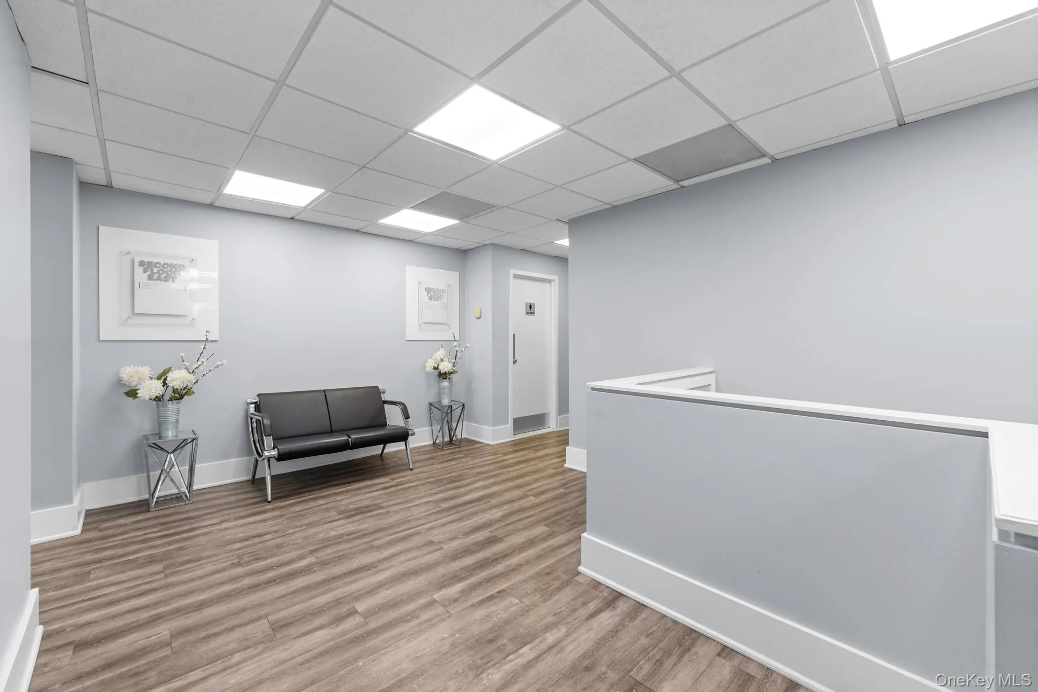 Lobby with restrooms area featuring an upstairs landing and a paneled ceiling Lobby with restrooms area featuring an upstairs landing and a paneled ceiling