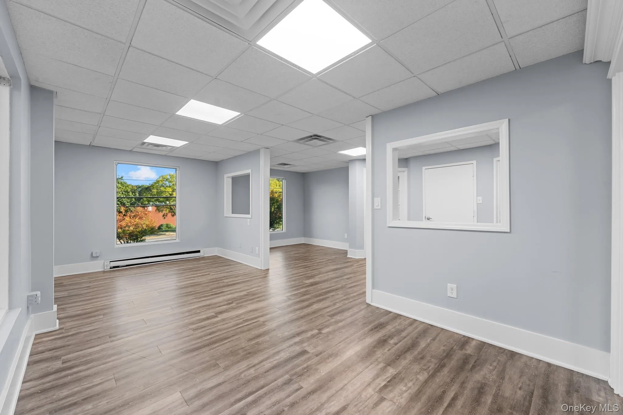 Main room featuring a baseboard radiator, wood finished floors, and a paneled ceiling Main room featuring a baseboard radiator, wood finished floors, and a paneled ceiling