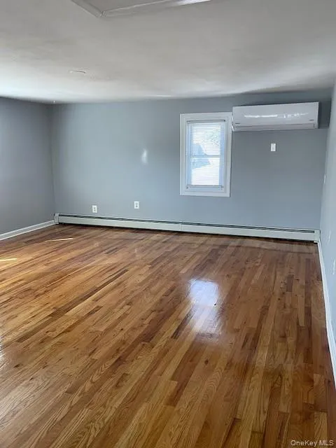 Hugh living area with gleaming hardwood floor, baseboard and mini split unit for cooling and heating Hugh living area with gleaming hardwood floor, baseboard and mini split unit for cooling and heating