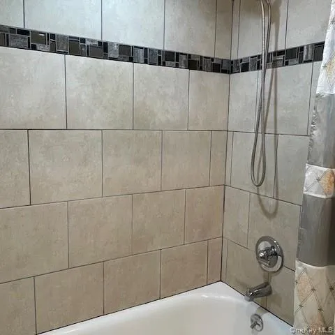 Hall bathroom offers tub/shower combo and tiled wall Hall bathroom offers tub/shower combo and tiled wall