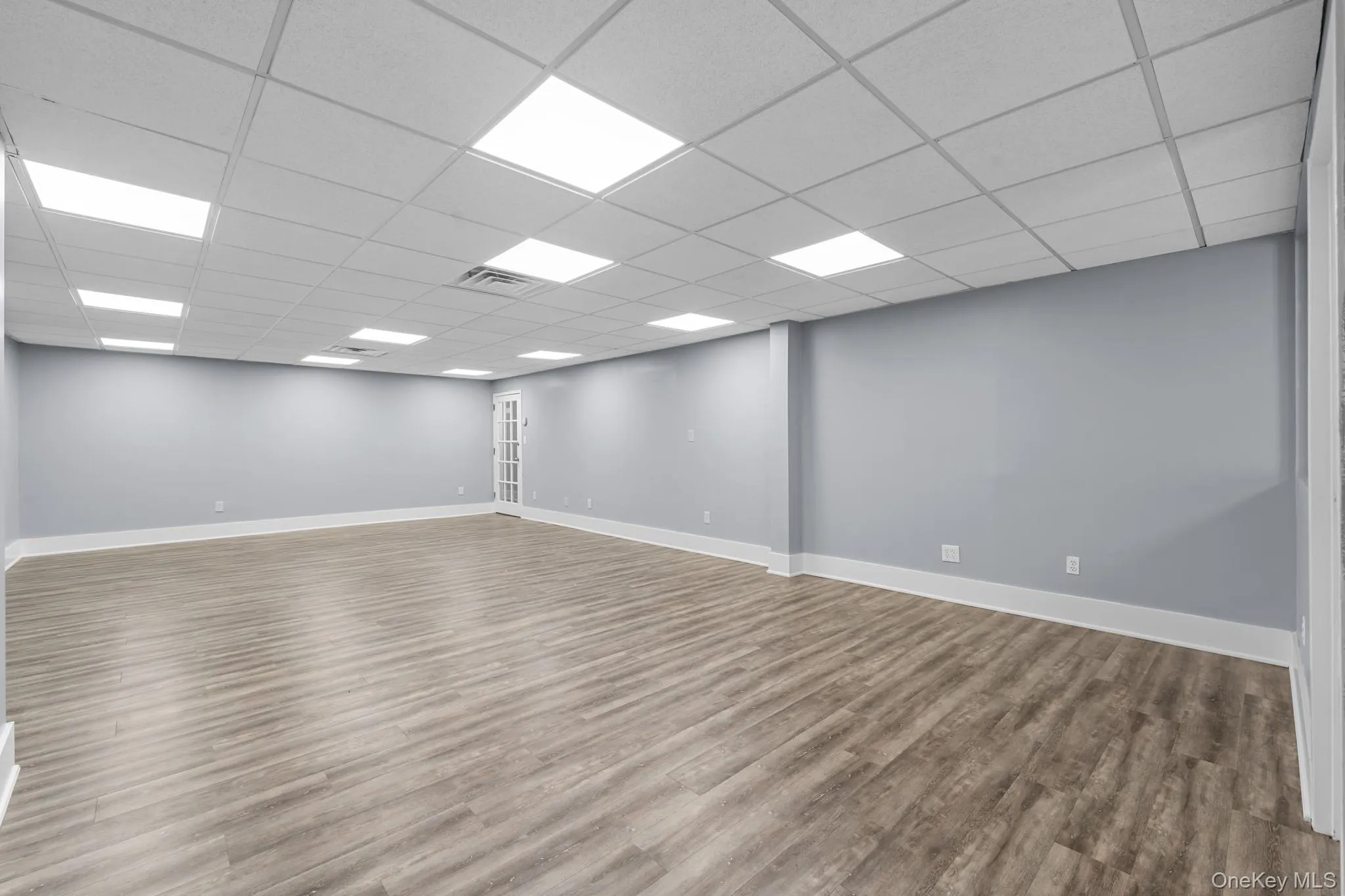 Main room with wood finished floors and a drop ceiling Main room with wood finished floors and a drop ceiling