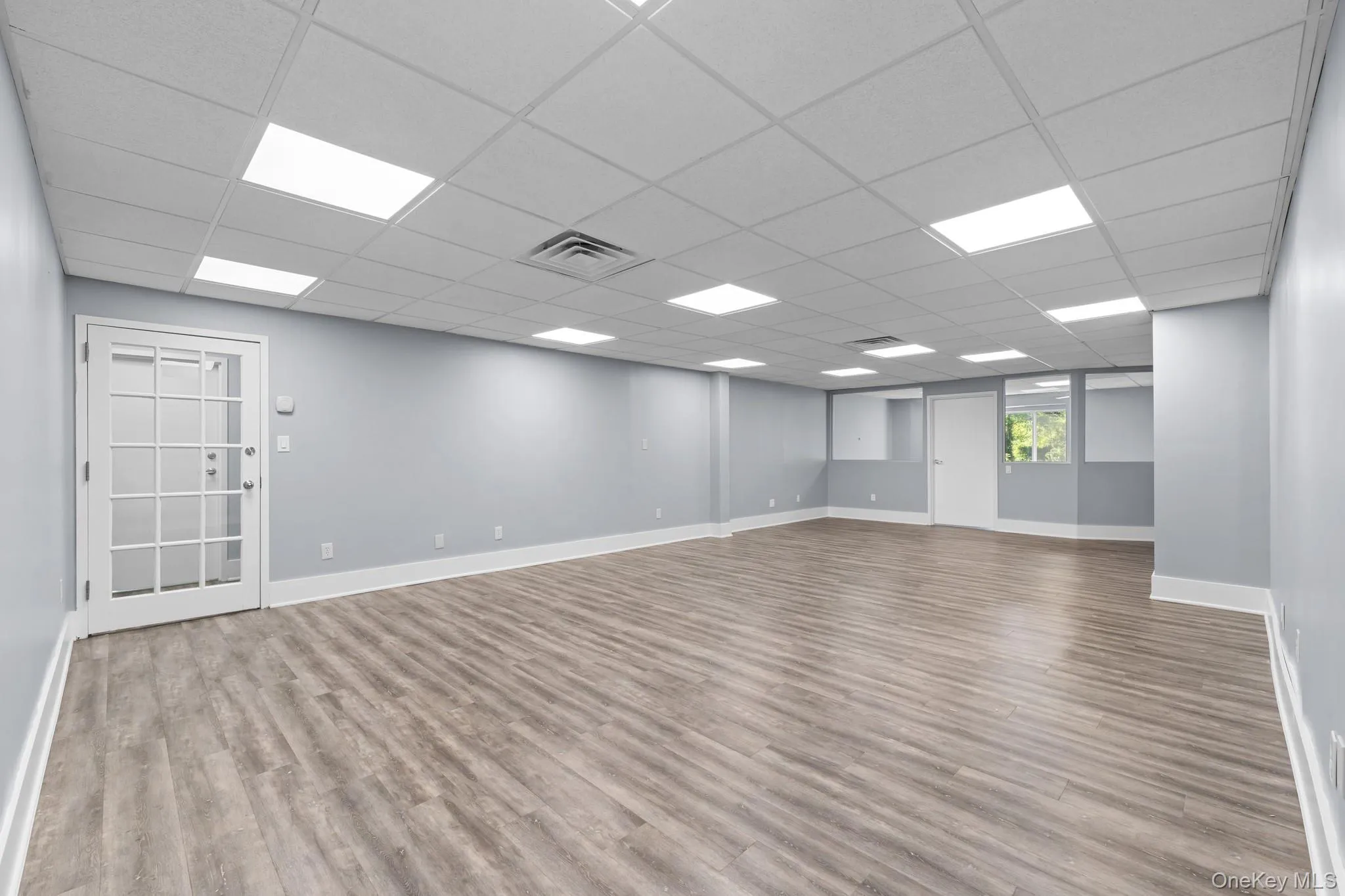 Main room with light wood-style flooring and a drop ceiling Main room with light wood-style flooring and a drop ceiling