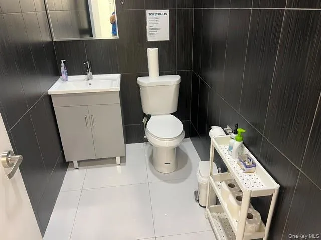 Half bathroom with vanity, light tile patterned floors, and tile walls Half bathroom with vanity, light tile patterned floors, and tile walls