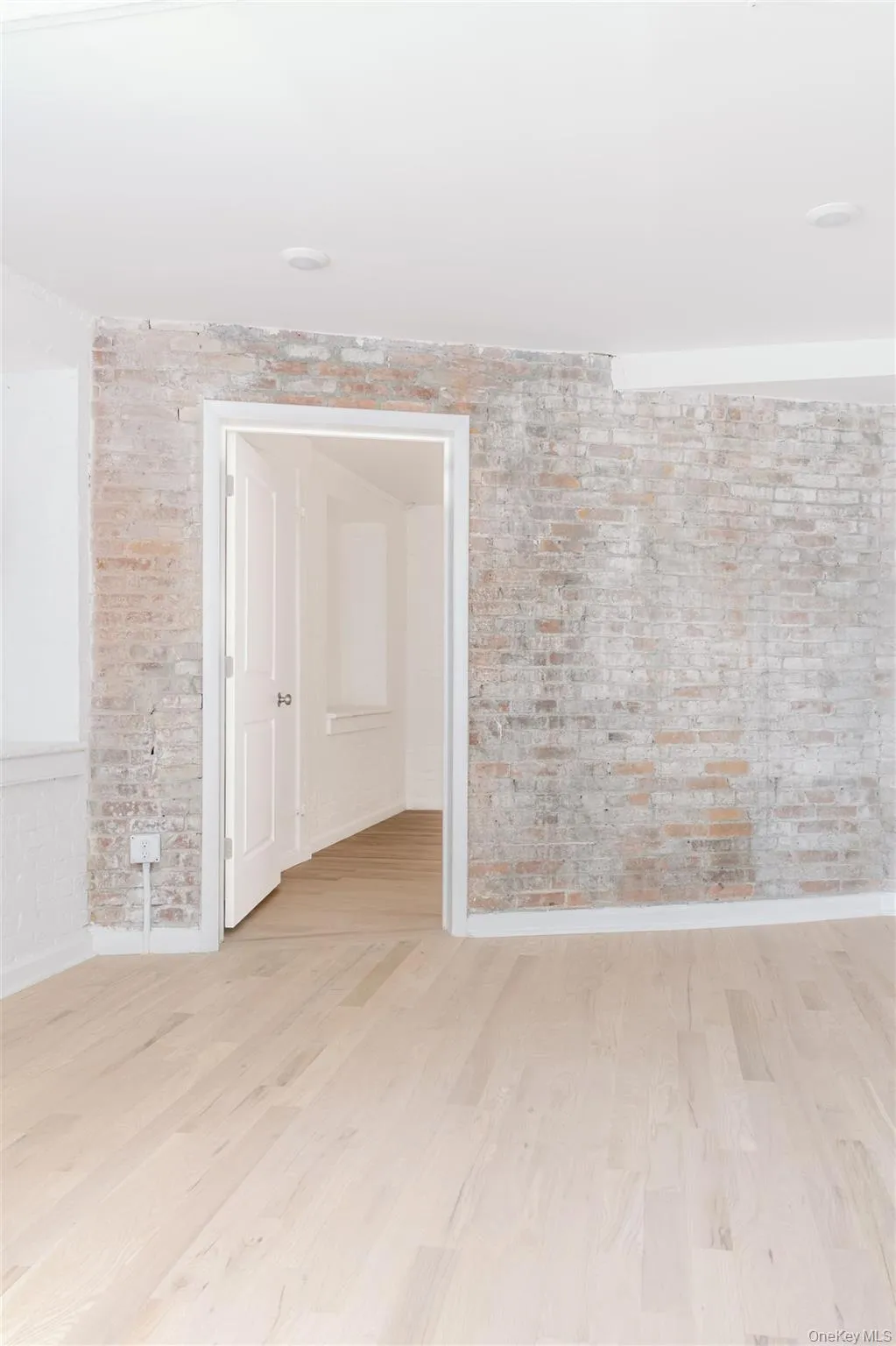 Spare room with wood finished floors and brick wall Spare room with wood finished floors and brick wall