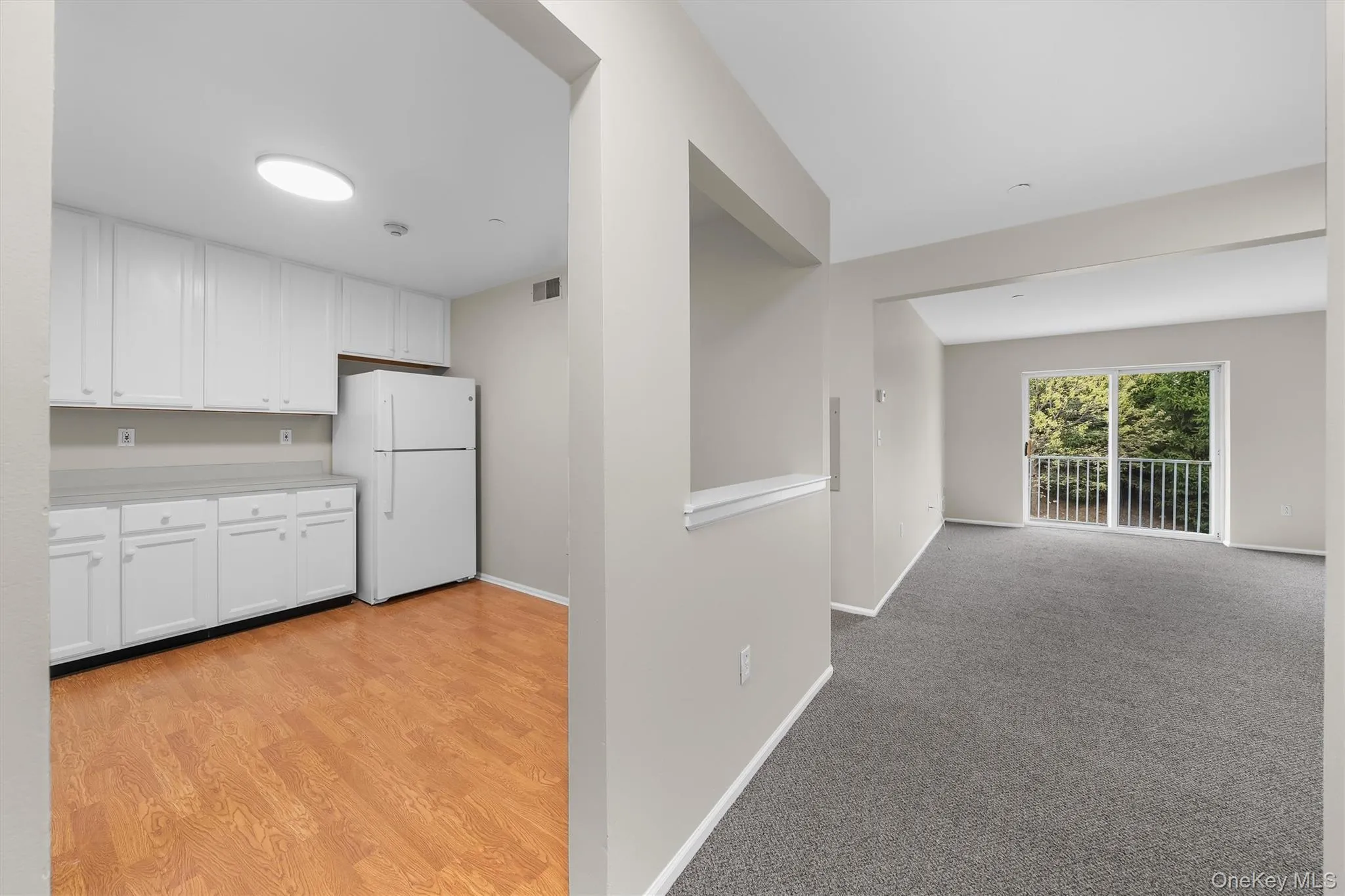 Kitchen with visible vents, baseboards, freestanding refrigerator, and white cabinetry Kitchen with visible vents, baseboards, freestanding refrigerator, and white cabinetry