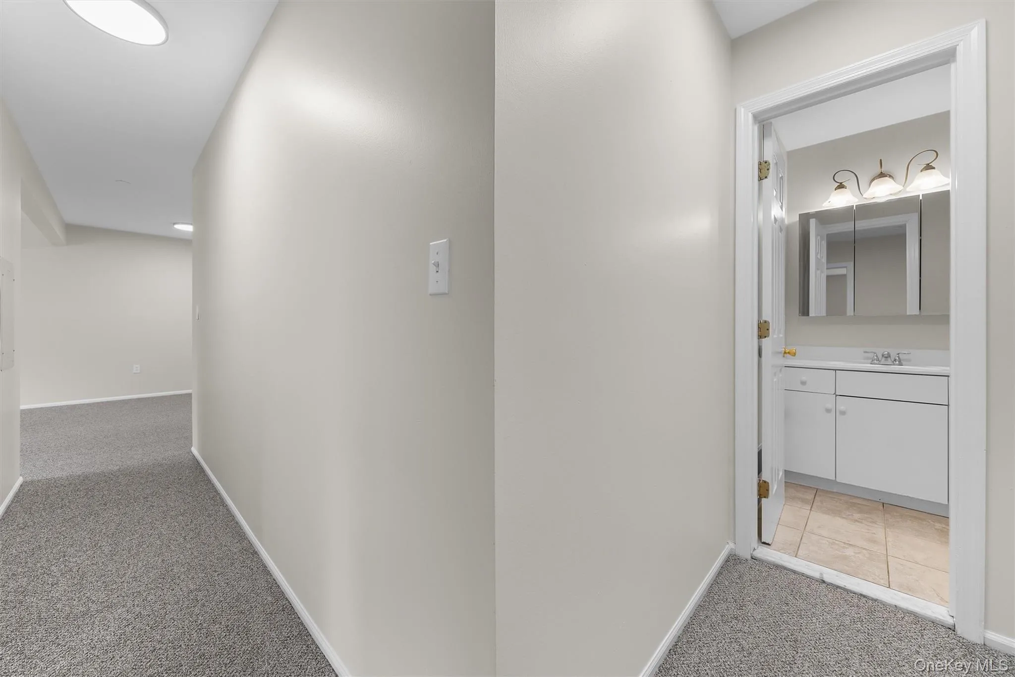 Hallway featuring a sink, light carpet, and baseboards Hallway featuring a sink, light carpet, and baseboards