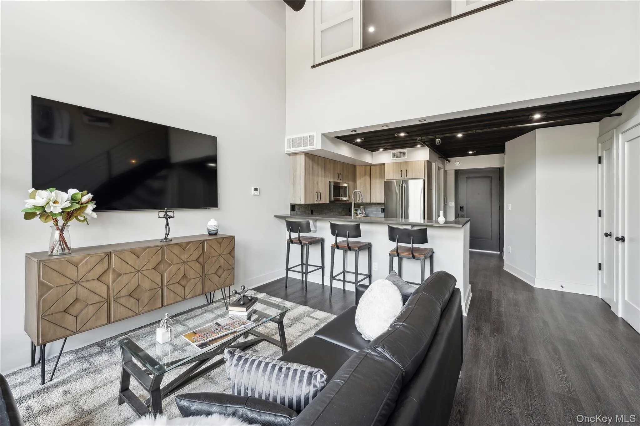 Living room featuring dark wood finished floors and a high ceiling Living room featuring dark wood finished floors and a high ceiling