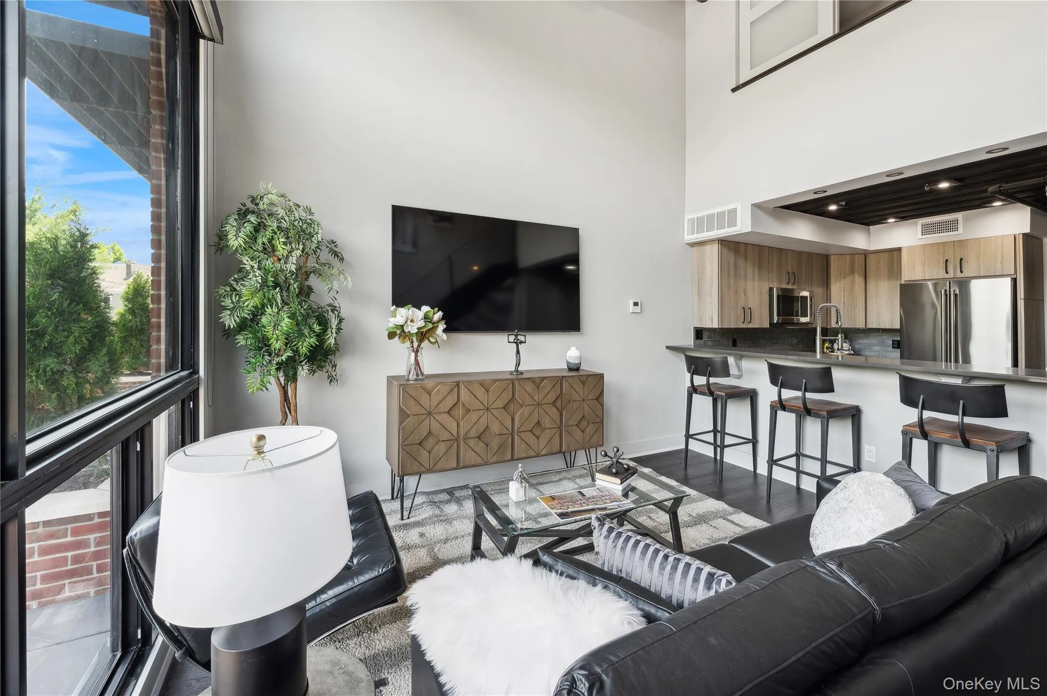 Living room featuring wood finished floors, a towering ceiling, and plenty of natural light Living room featuring wood finished floors, a towering ceiling, and plenty of natural light