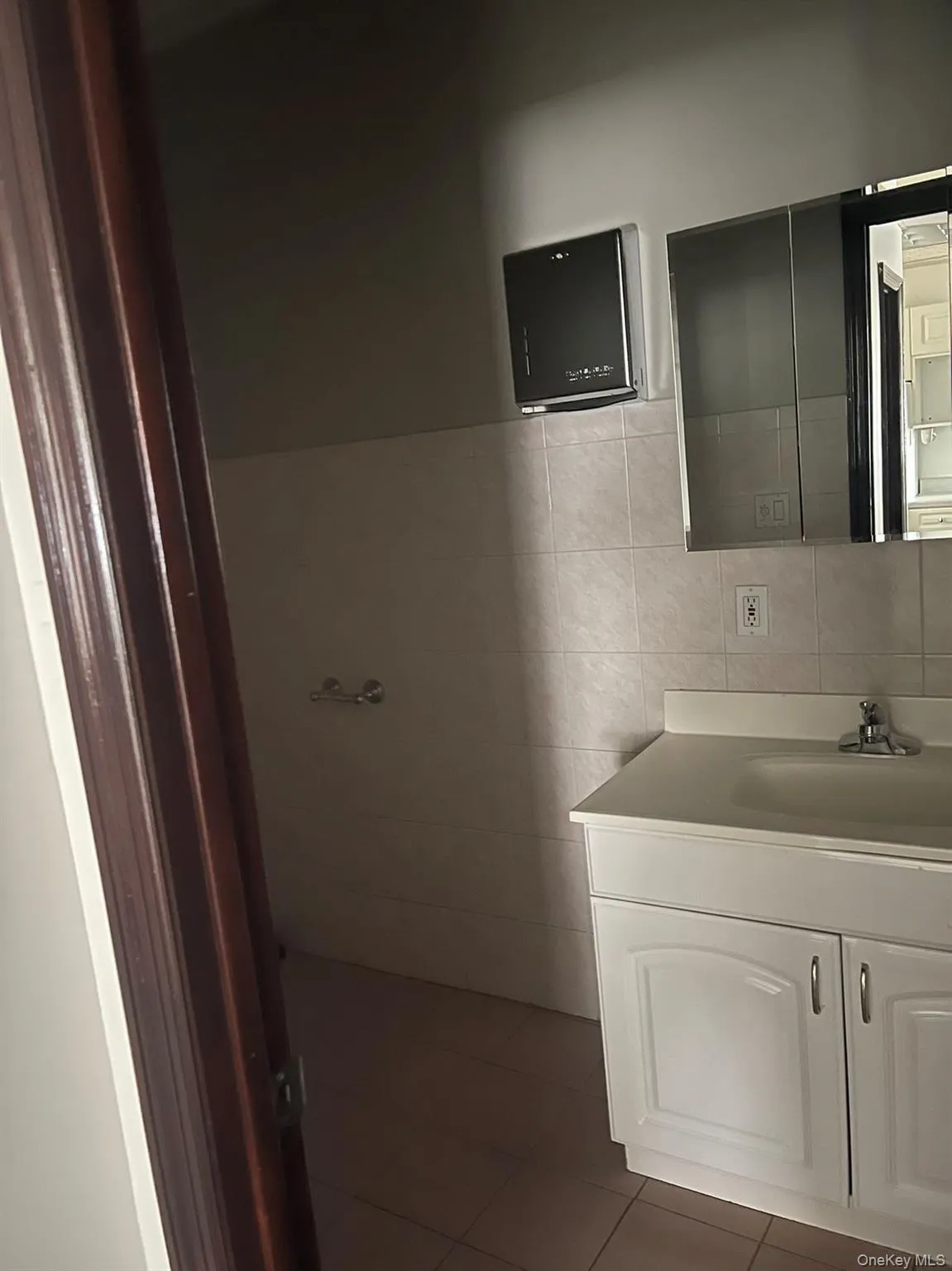 Bathroom featuring tile walls, dark tile patterned flooring, and vanity Bathroom featuring tile walls, dark tile patterned flooring, and vanity