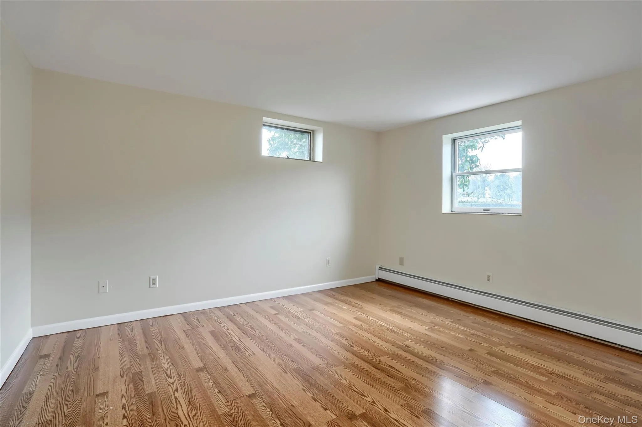 Unfurnished room with light wood-style flooring and a baseboard radiator Unfurnished room with light wood-style flooring and a baseboard radiator
