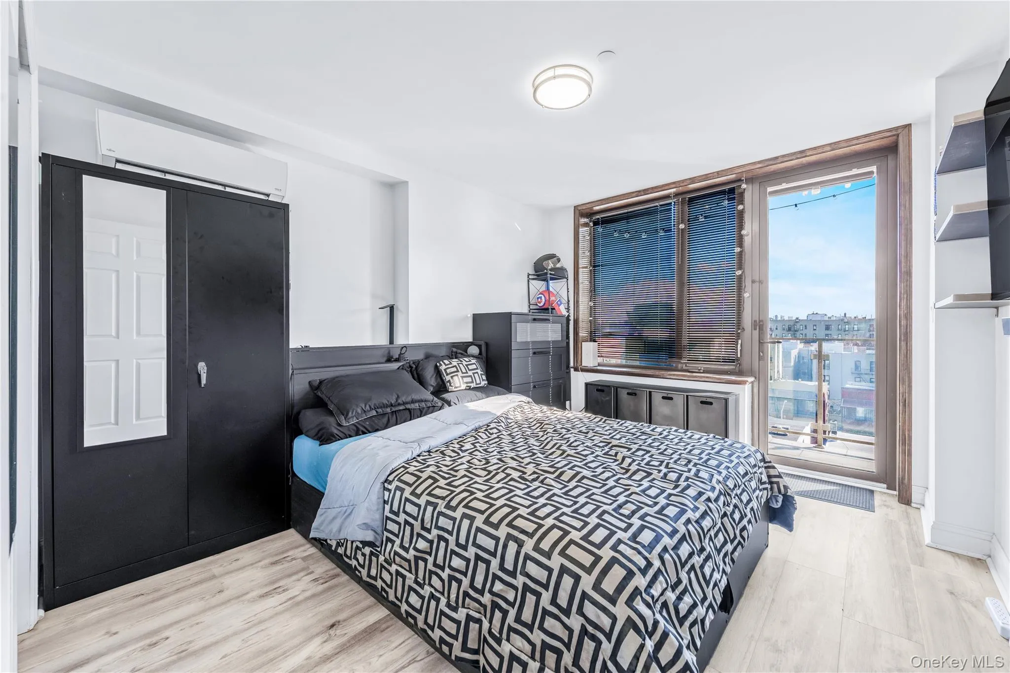 Bedroom featuring a wall of windows, light wood-style flooring, a wall mounted AC, and access to outside Bedroom featuring a wall of windows, light wood-style flooring, a wall mounted AC, and access to outside