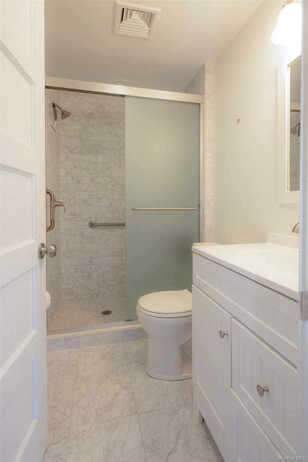 Full bath featuring vanity, a stall shower, and light marble finish flooring Full bath featuring vanity, a stall shower, and light marble finish flooring