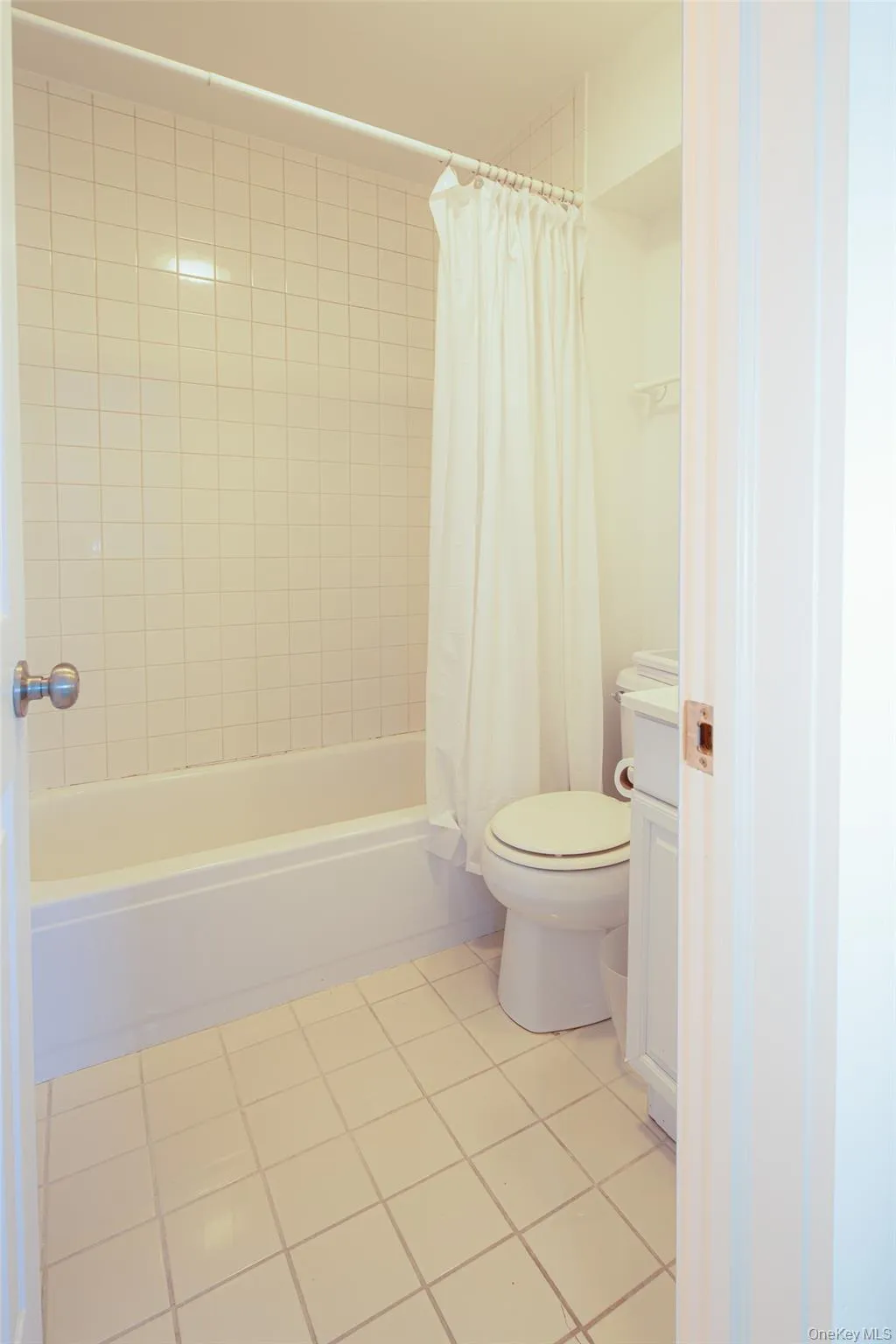 Full bathroom with light tile patterned flooring, shower / tub combo with curtain, and vanity Full bathroom with light tile patterned flooring, shower / tub combo with curtain, and vanity