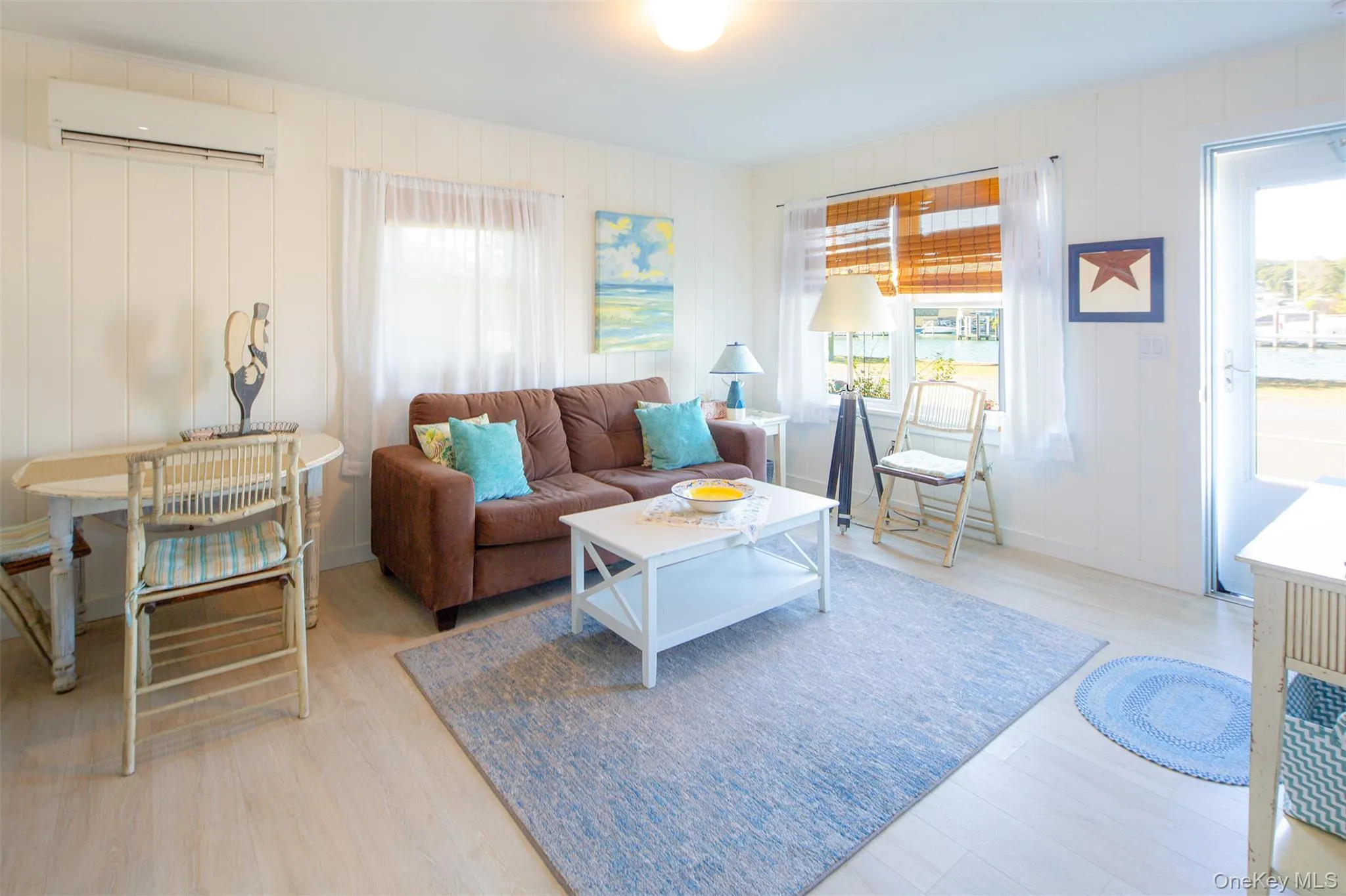 Living room with healthy amount of natural light, light wood-style flooring, and a wall mounted air conditioner Living room with healthy amount of natural light, light wood-style flooring, and a wall mounted air conditioner