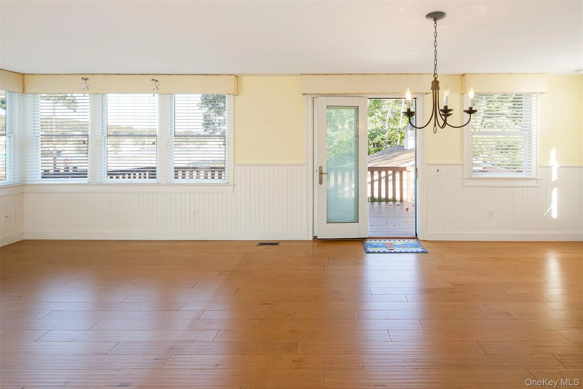 Unfurnished dining area featuring wood finished floors, a wainscoted wall, and a chandelier Unfurnished dining area featuring wood finished floors, a wainscoted wall, and a chandelier