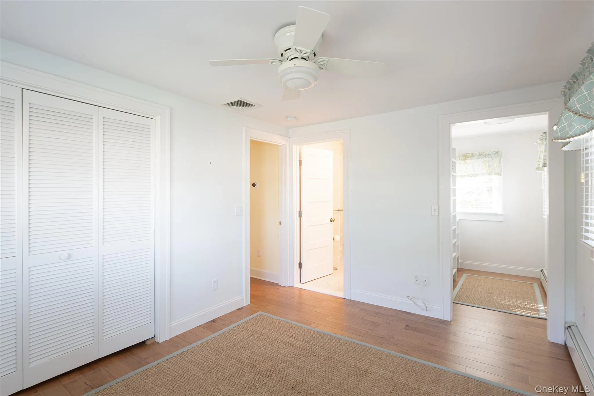 Unfurnished bedroom featuring hardwood / wood-style floors, baseboard heating, a closet, a ceiling fan, and ensuite bath Unfurnished bedroom featuring hardwood / wood-style floors, baseboard heating, a closet, a ceiling fan, and ensuite bath