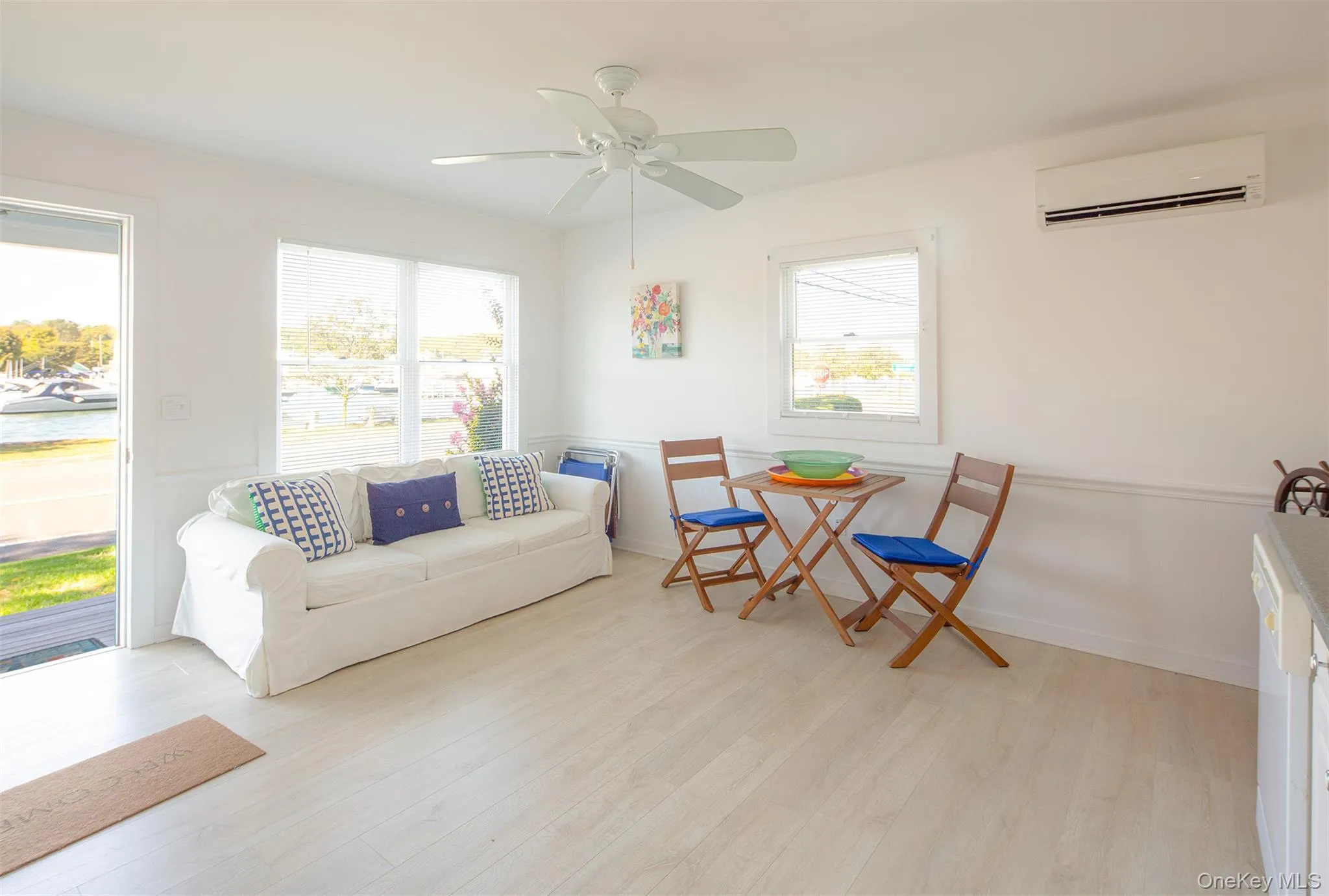 Living area with light wood-style flooring, a wall unit AC, and ceiling fan Living area with light wood-style flooring, a wall unit AC, and ceiling fan