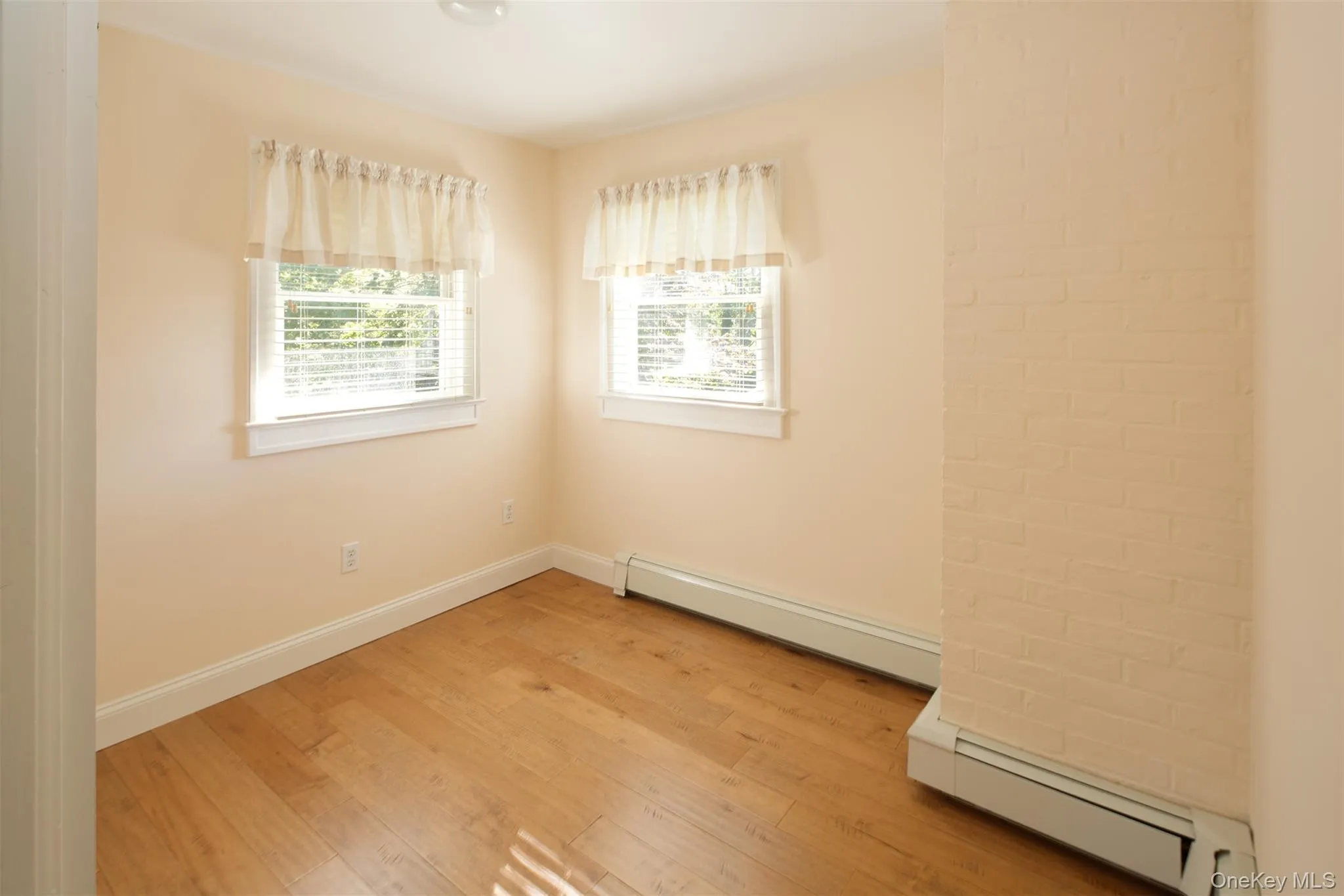 Empty room featuring a baseboard heating unit and light wood-style flooring Empty room featuring a baseboard heating unit and light wood-style flooring