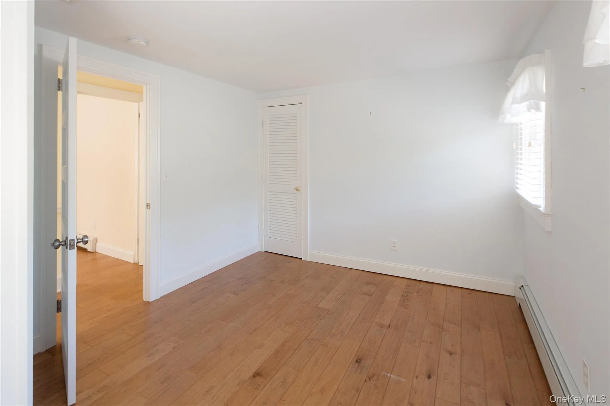 Unfurnished room featuring baseboard heating and light wood-type flooring Unfurnished room featuring baseboard heating and light wood-type flooring
