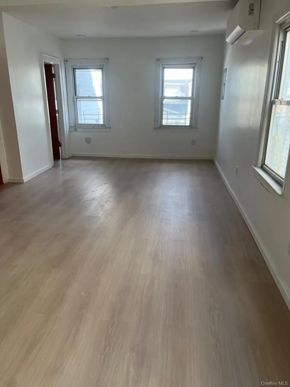 Spare room featuring wood finished floors, healthy amount of natural light, and a wall mounted air conditioner Spare room featuring wood finished floors, healthy amount of natural light, and a wall mounted air conditioner