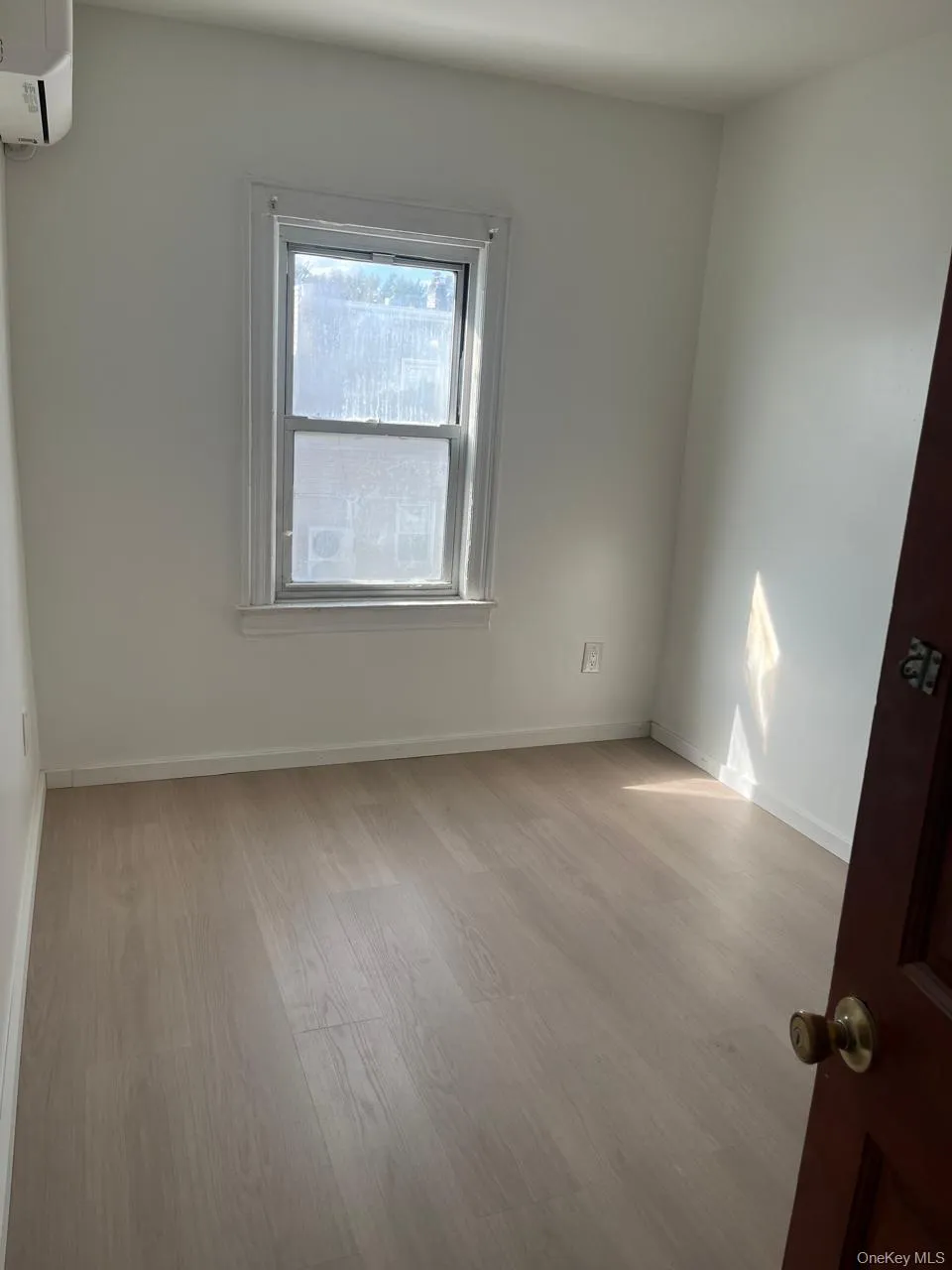 Unfurnished room featuring light wood-style floors and a wall mounted AC Unfurnished room featuring light wood-style floors and a wall mounted AC