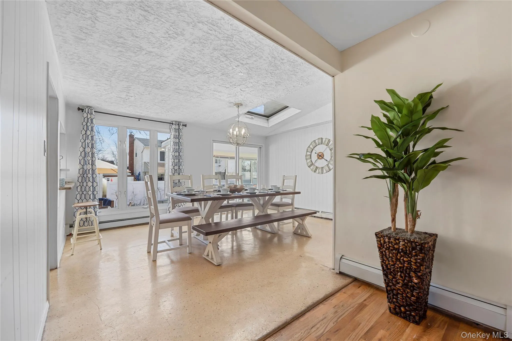 Dining room with baseboard heating, a chandelier, a baseboard radiator, and a textured ceiling Dining room with baseboard heating, a chandelier, a baseboard radiator, and a textured ceiling