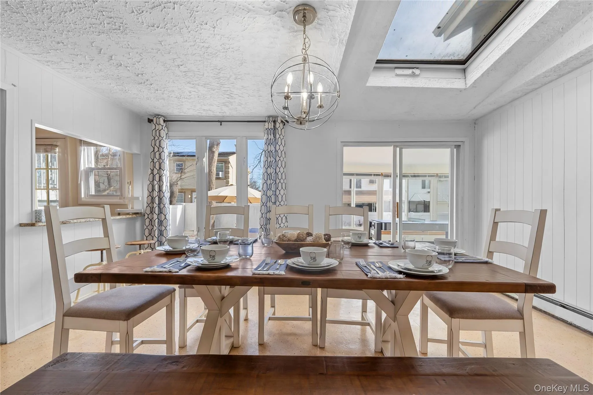 Dining area with wood walls, healthy amount of natural light, a chandelier, and a textured ceiling Dining area with wood walls, healthy amount of natural light, a chandelier, and a textured ceiling