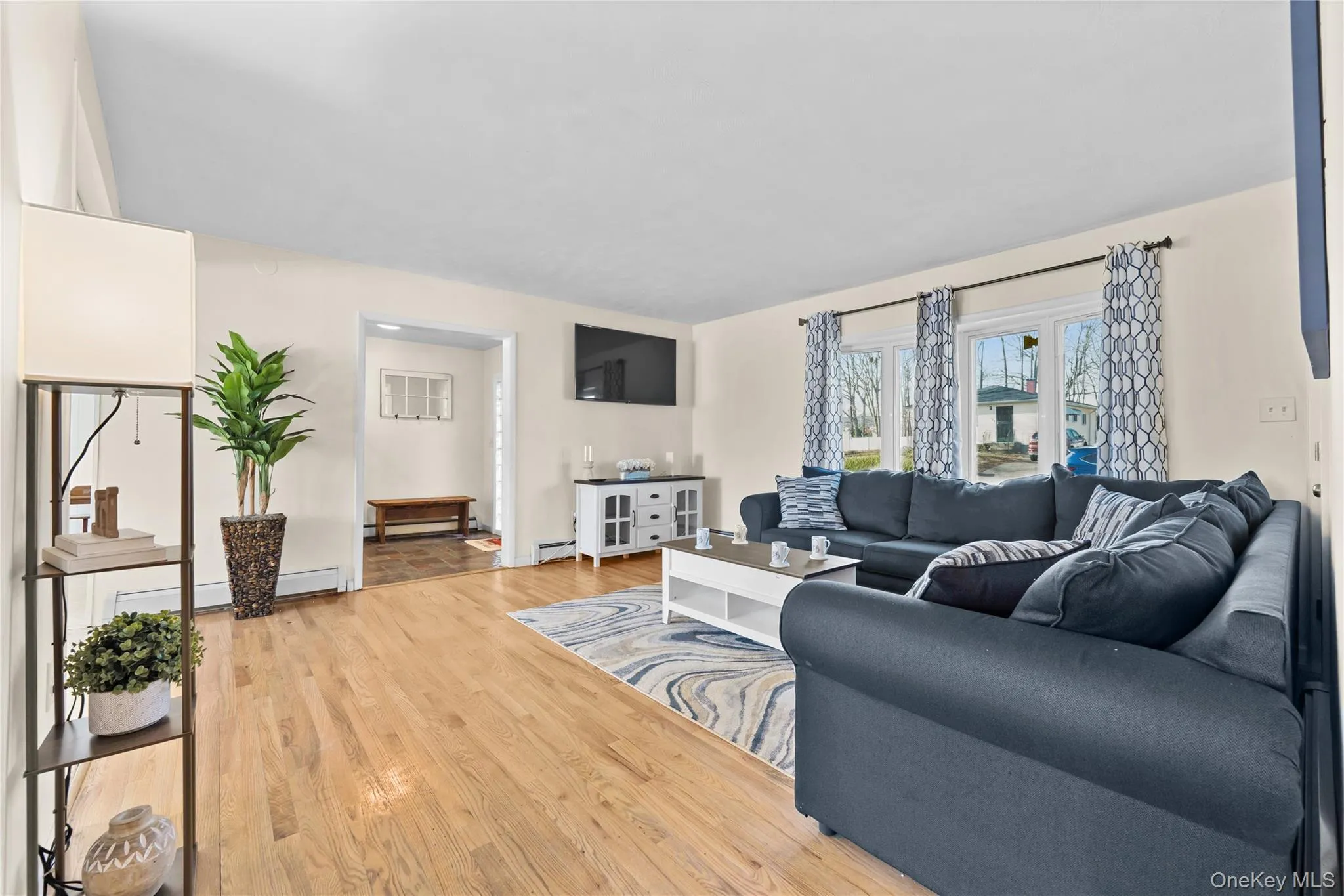 Living room with wood finished floors, a baseboard heating unit, and a baseboard radiator Living room with wood finished floors, a baseboard heating unit, and a baseboard radiator