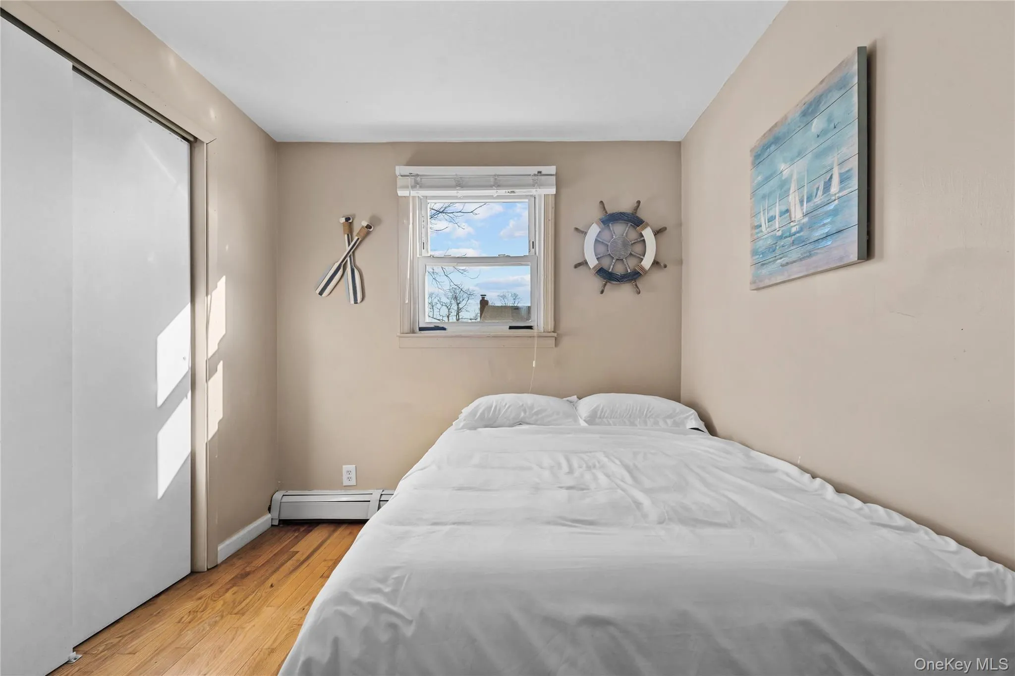 Bedroom with light wood-style floors, a baseboard heating unit, and a closet Bedroom with light wood-style floors, a baseboard heating unit, and a closet